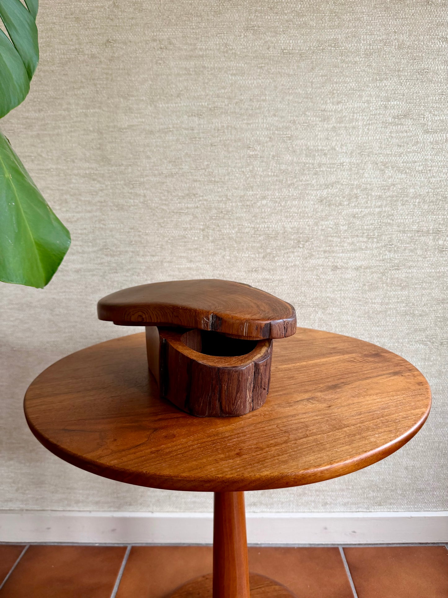 Wooden side table with a unique design against a textured wall.