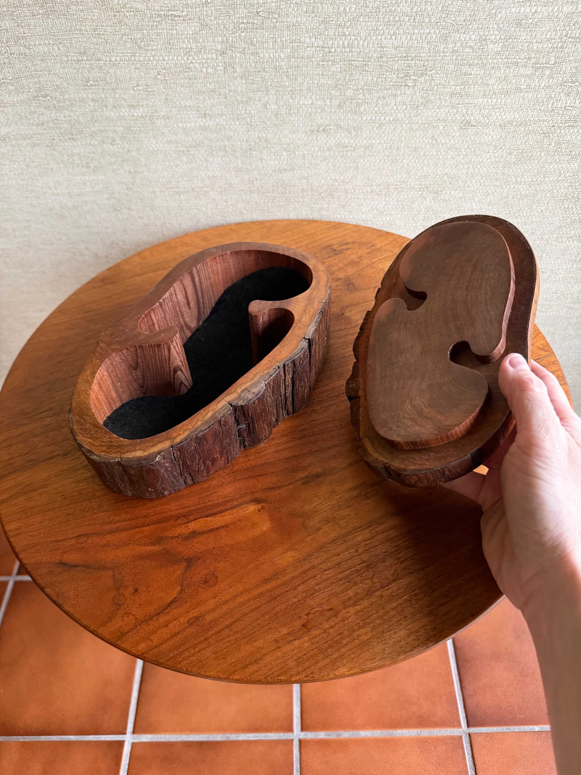 Wooden cat litter box with a paw-shaped entrance on a tiled floor.