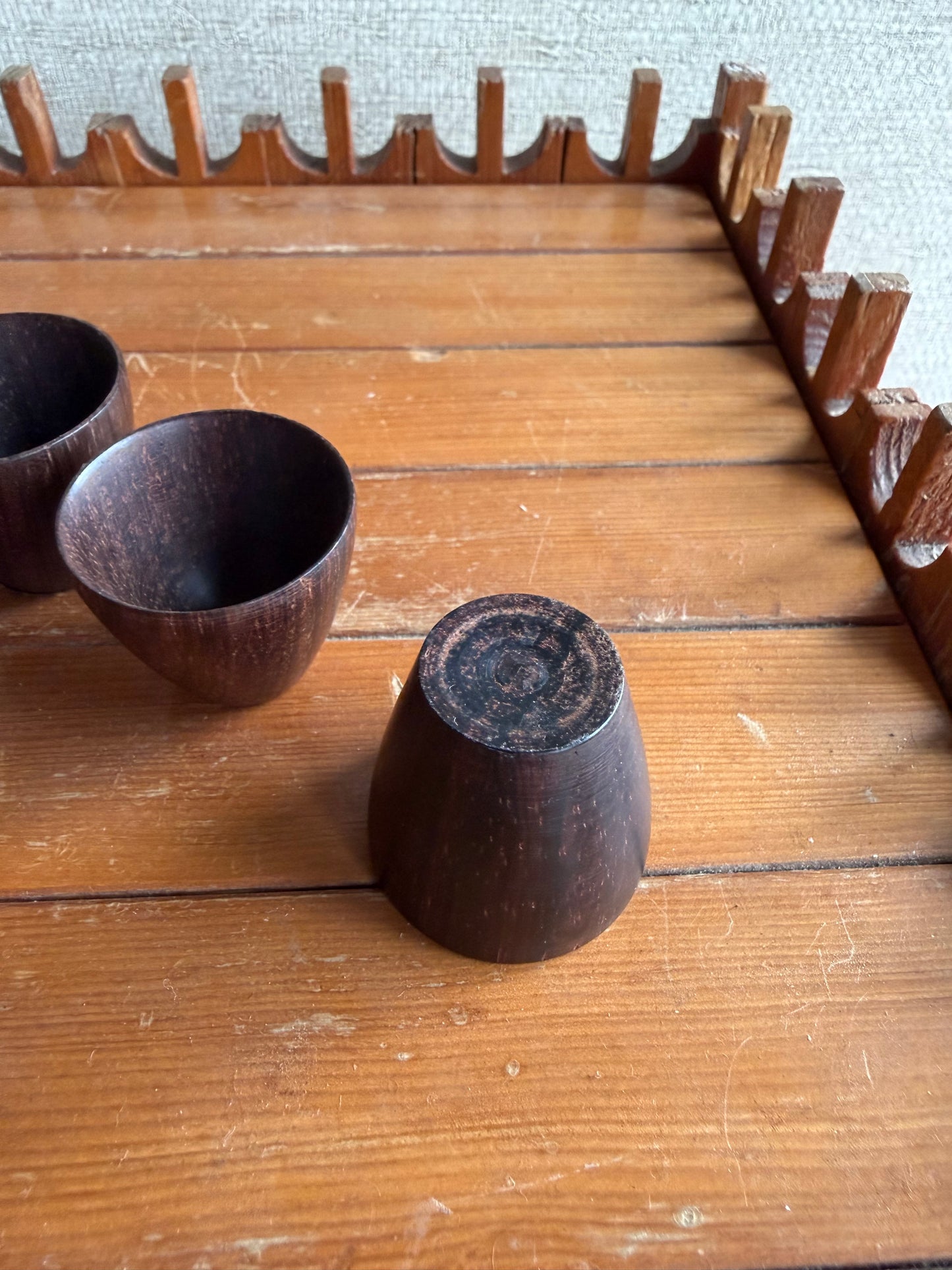 Wooden cups and a wooden block on a wooden surface with a textured wall background