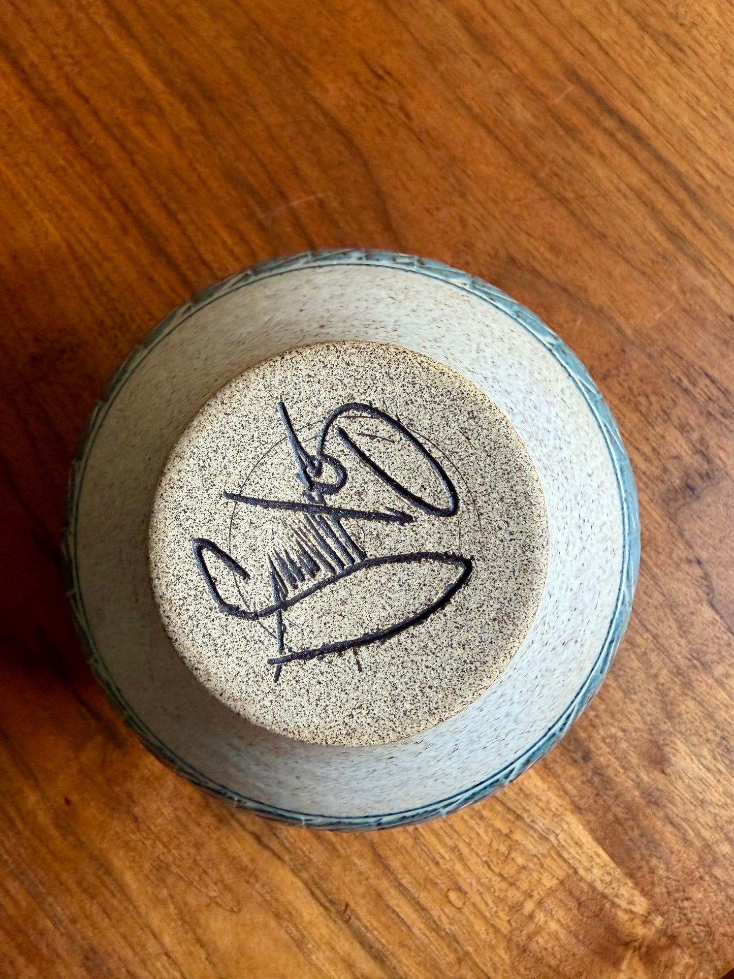 Ceramic bowl with a signature on a wooden surface