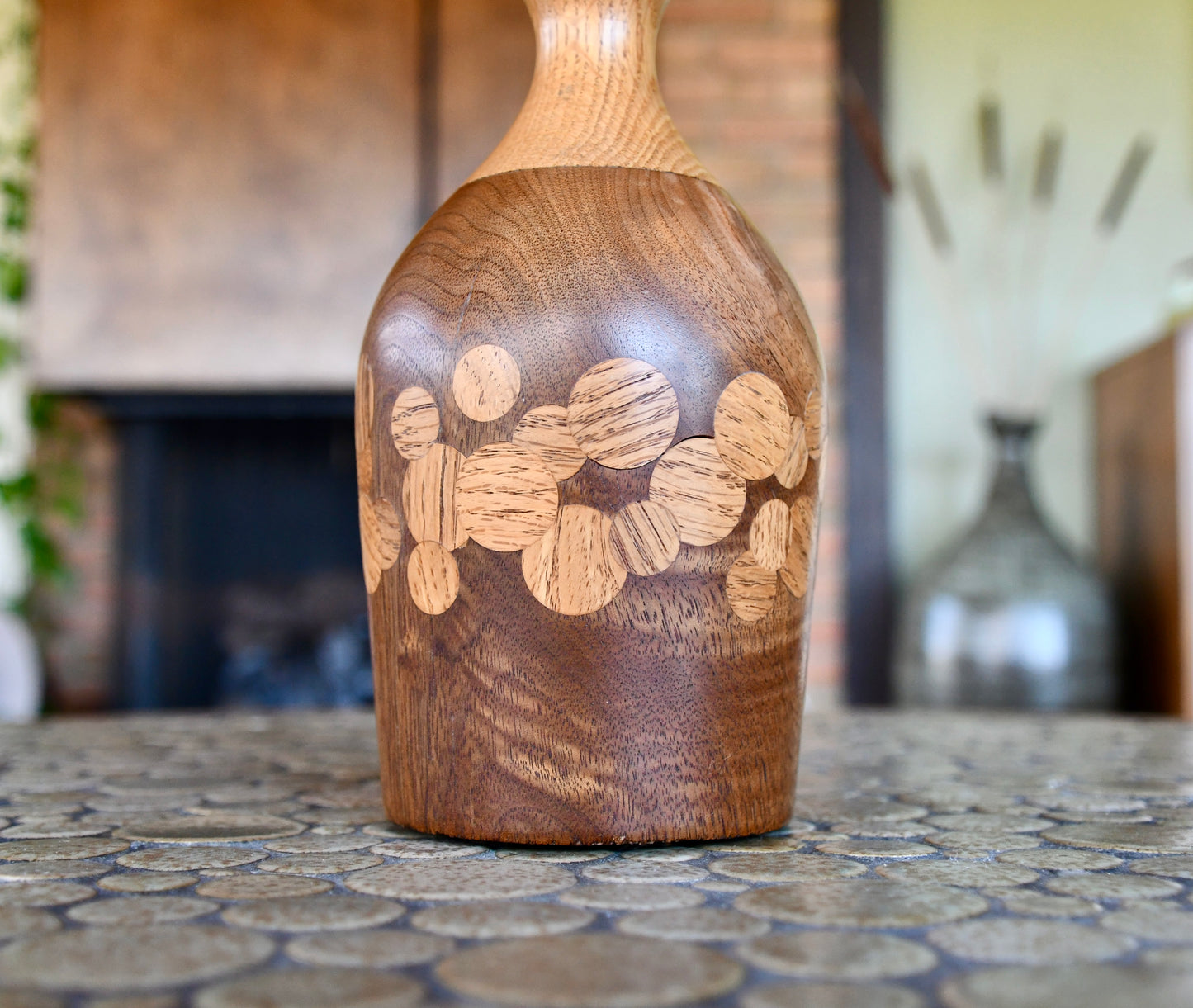Wooden bottle with circular carvings on a textured surface