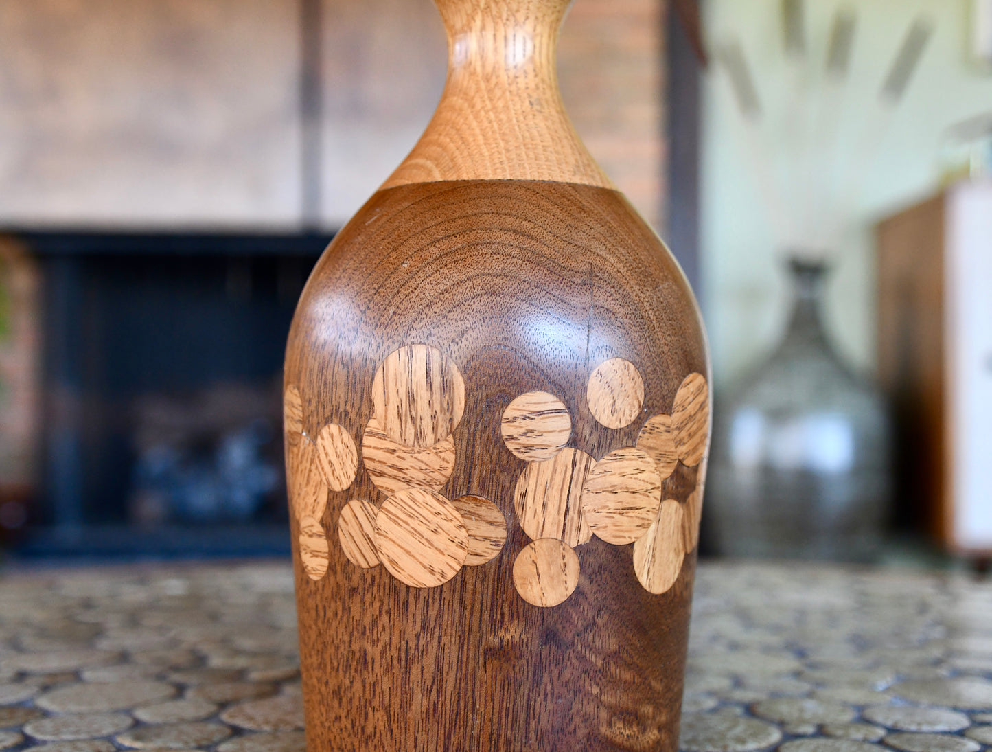 Wooden vase with engraved design on a textured surface