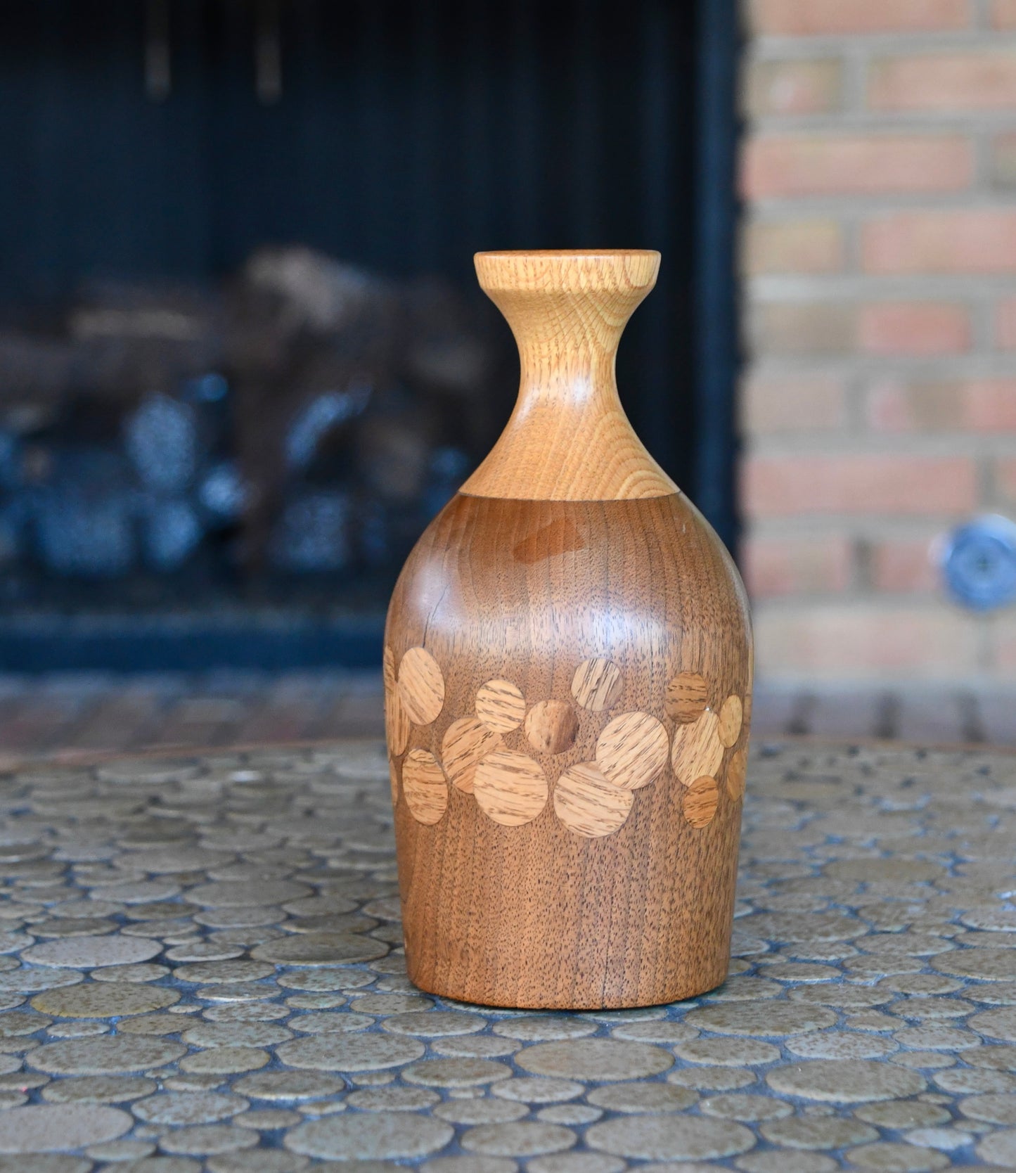 Wooden vase with engraved design on a stone surface