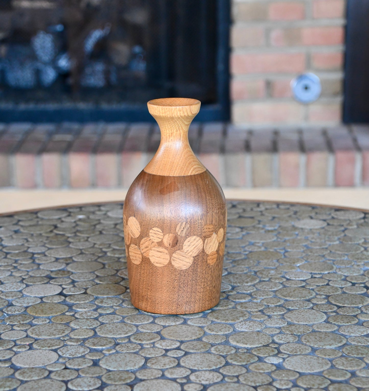 Wooden vase with floral patterns on a stone surface