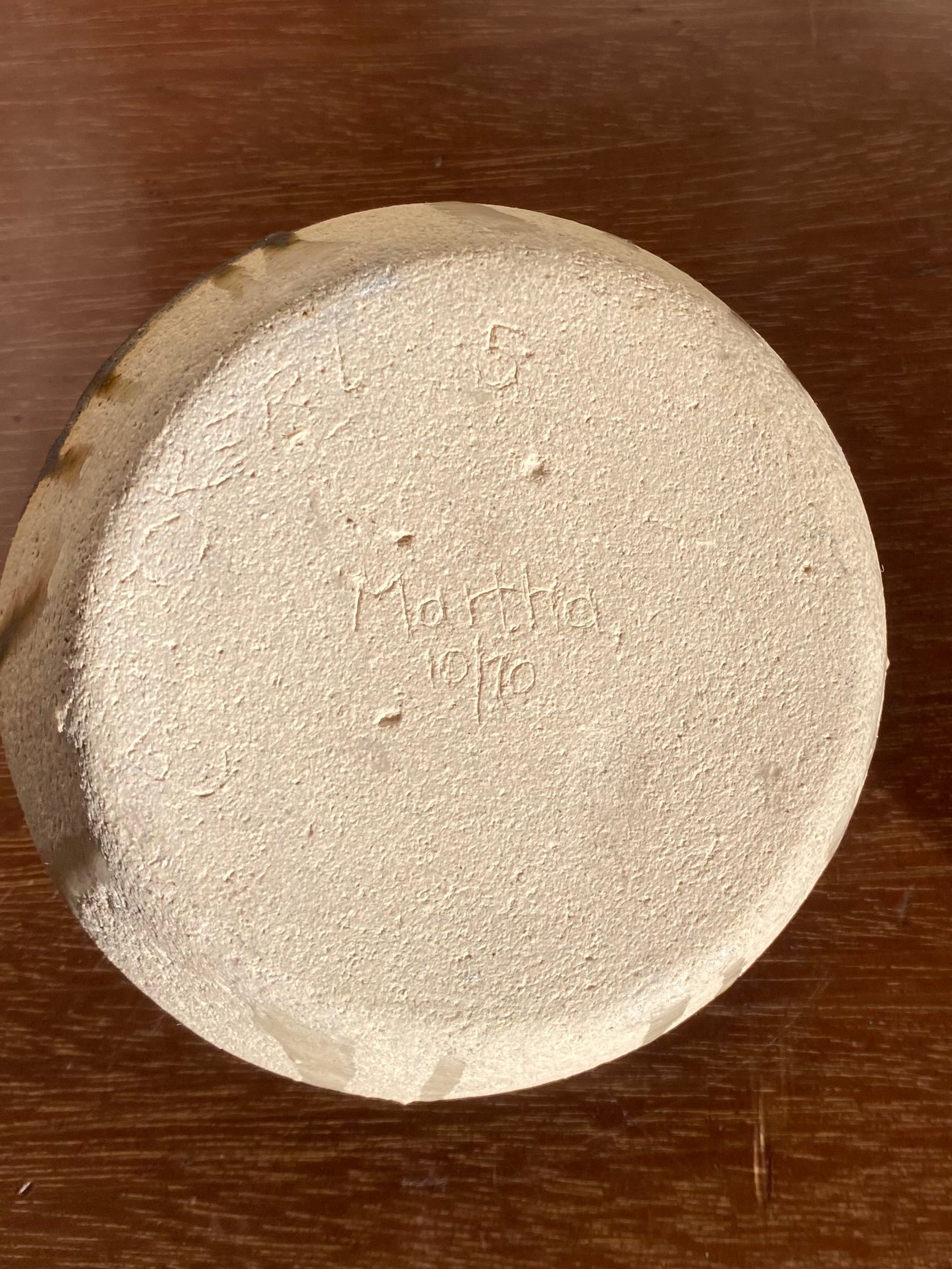 Round ceramic object with Martha and '1970' engraved on a pottery surface