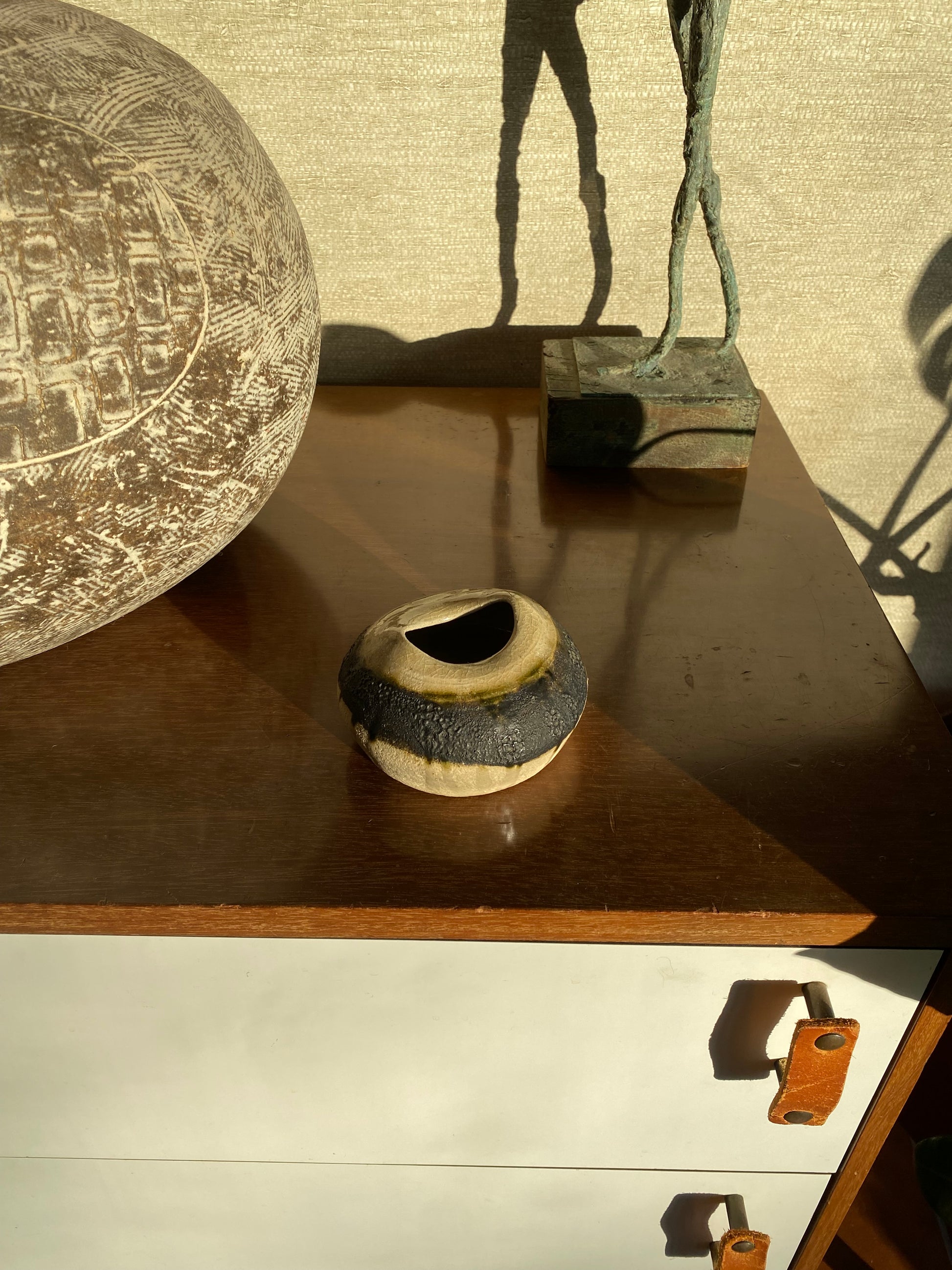Decorative objects including a spherical textured item, a cylindrical object with a hole, and a branch on a textured surface.