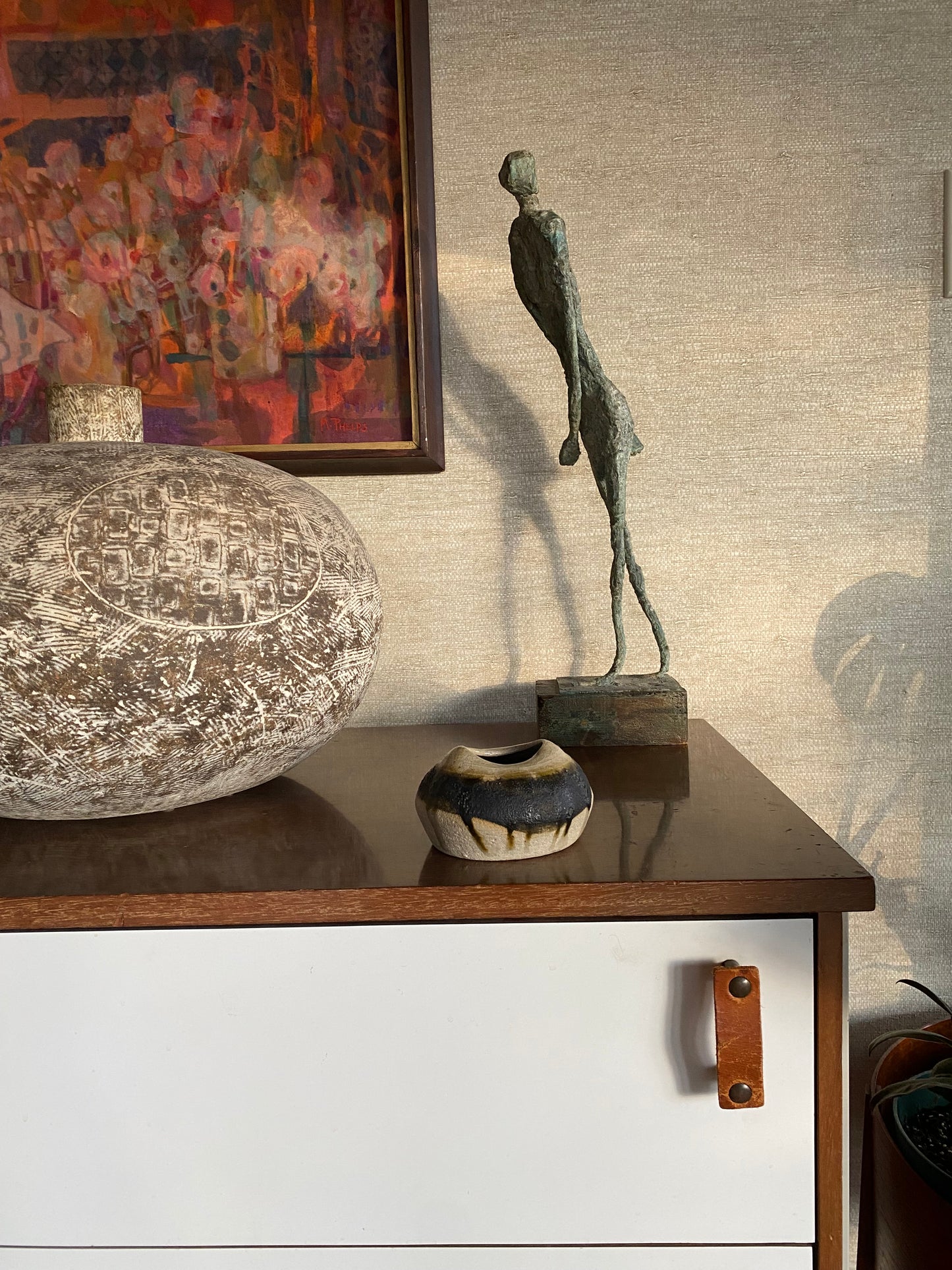Decorative elements including a sculpture, vase, and framed artwork on a textured wall.