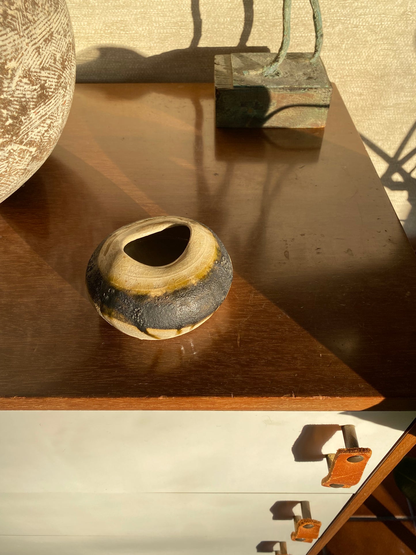 Ceramic vase on a wooden surface with a textured wall in the background