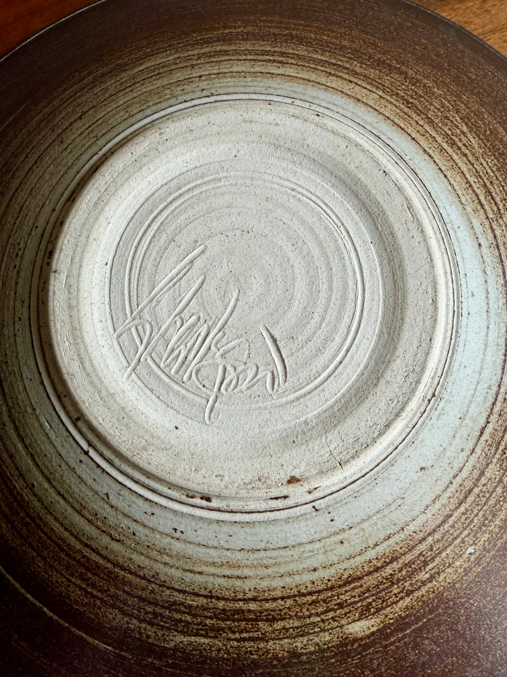 Close-up of a ceramic plate with a signature on the bottom