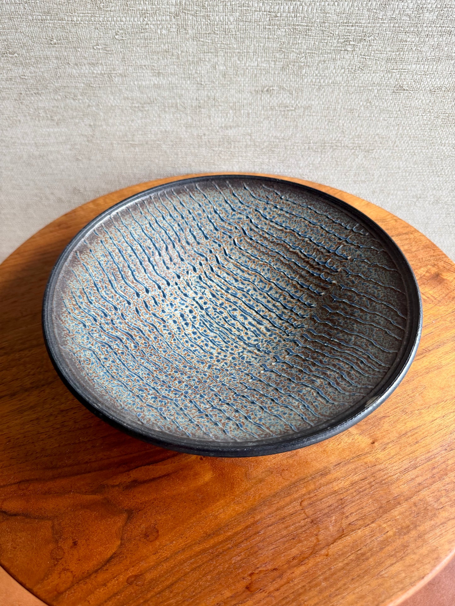 Black ceramic bowl with textured surface on a wooden surface