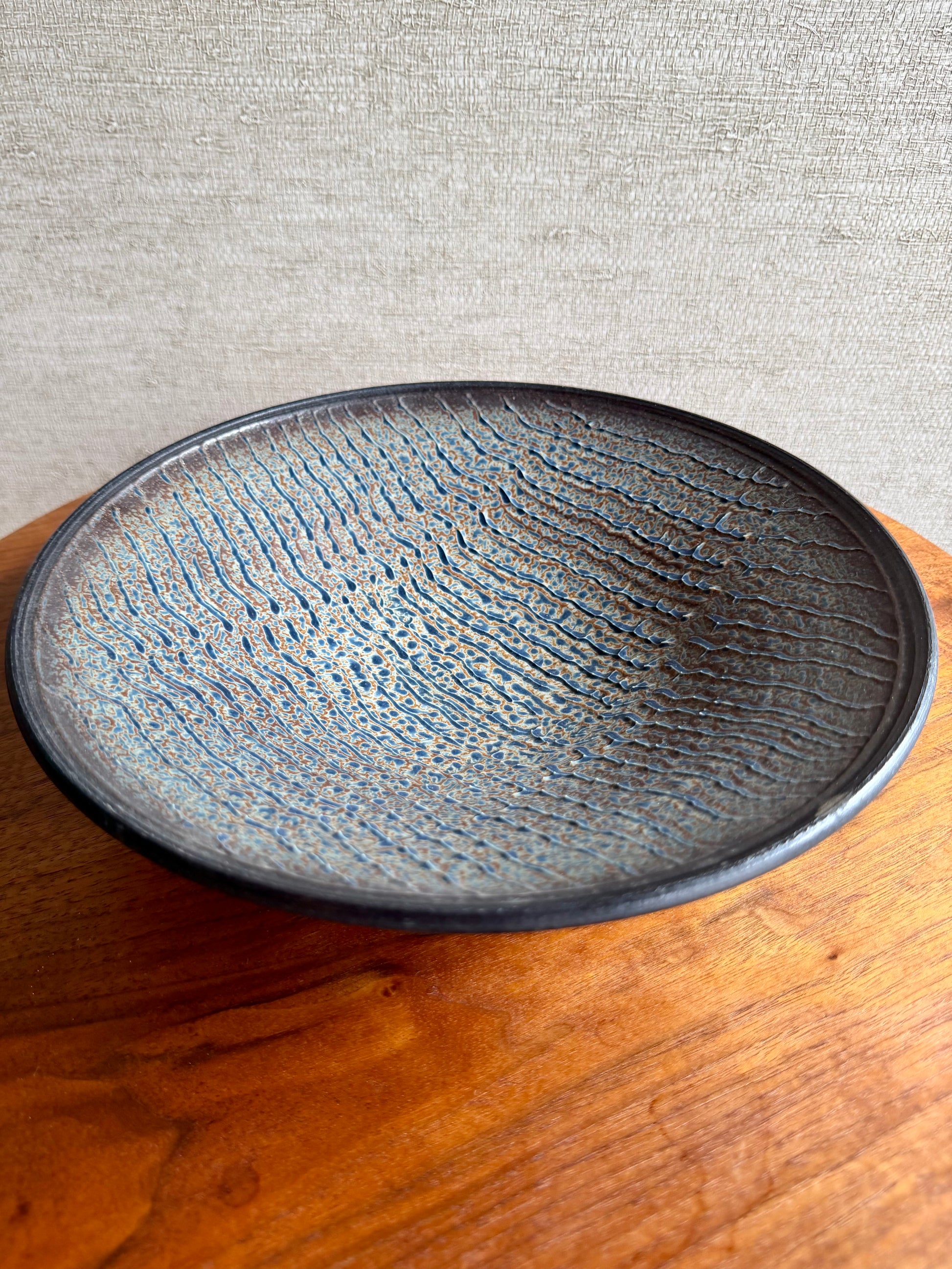 Black ceramic plate with textured surface on a wooden surface