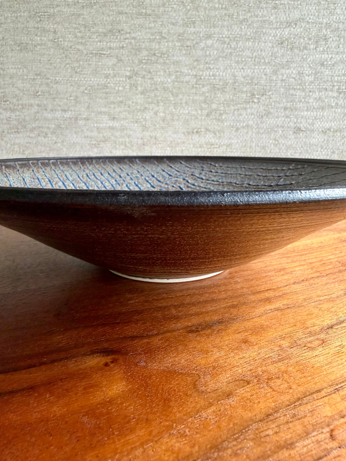 Wooden bowl on a wooden surface with a textured gray background