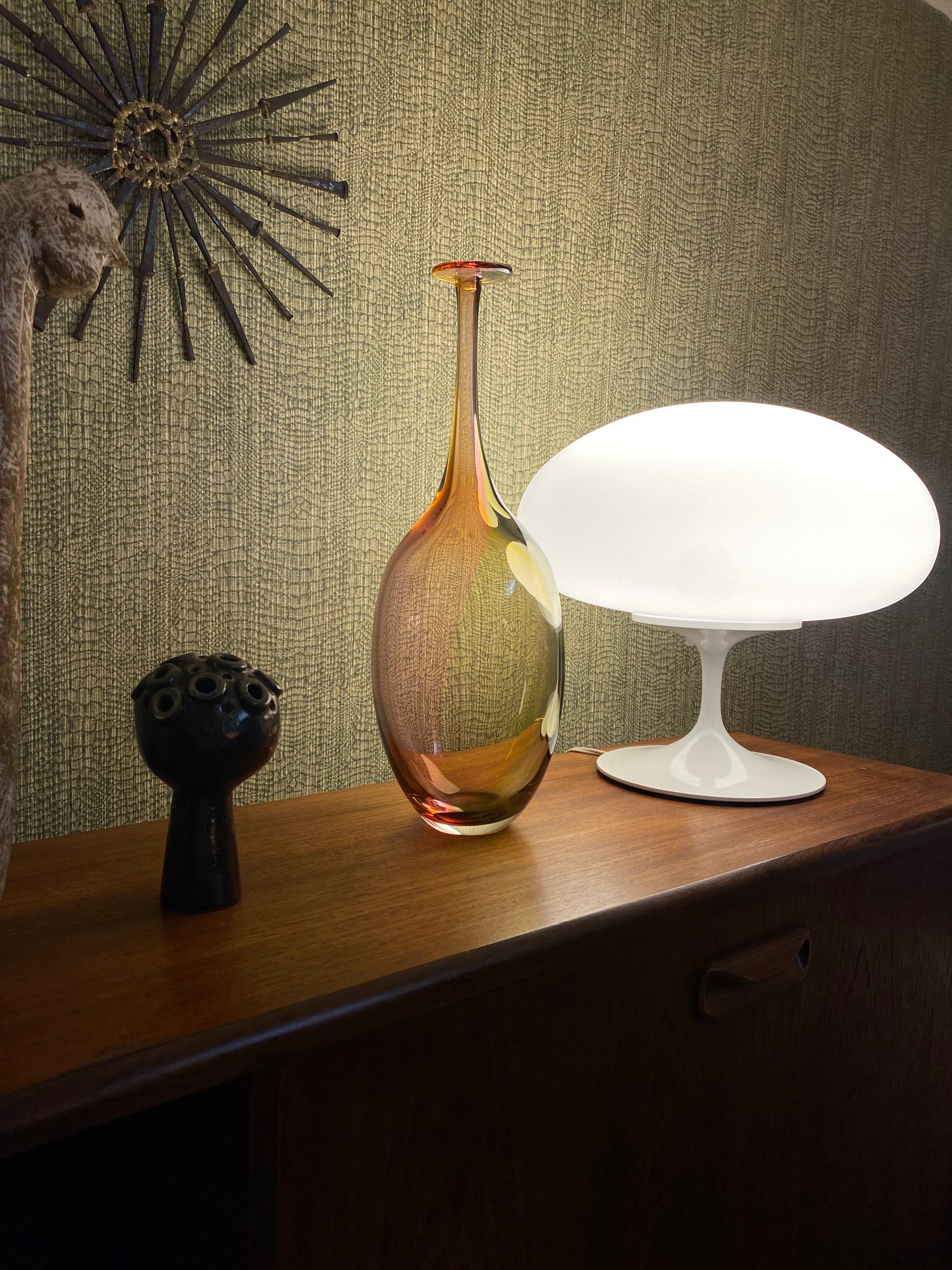 Decorative lamp with a gold base and white shade on a textured surface.
