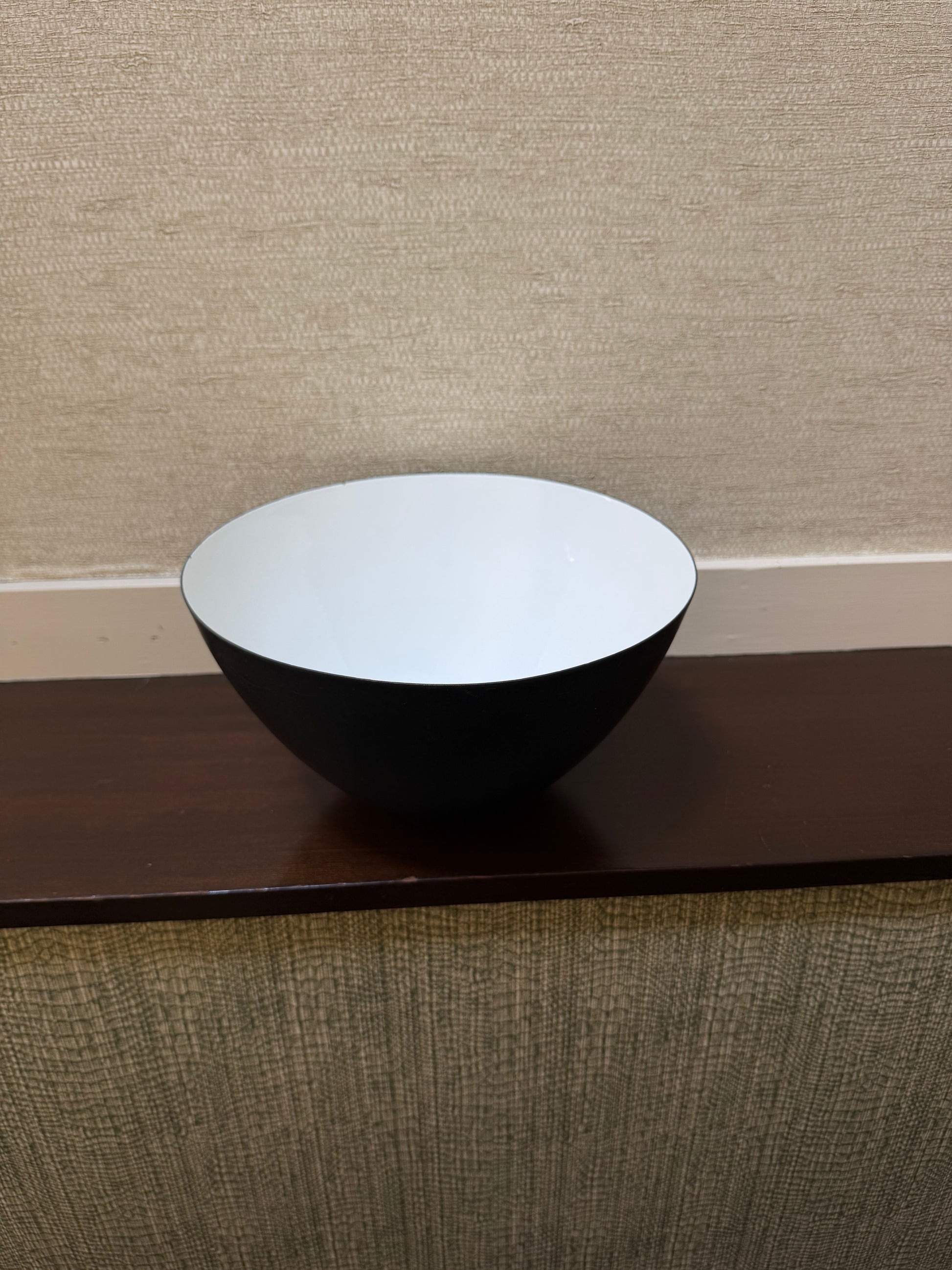Close-up of a black and white cylindrical object against a textured beige wall.