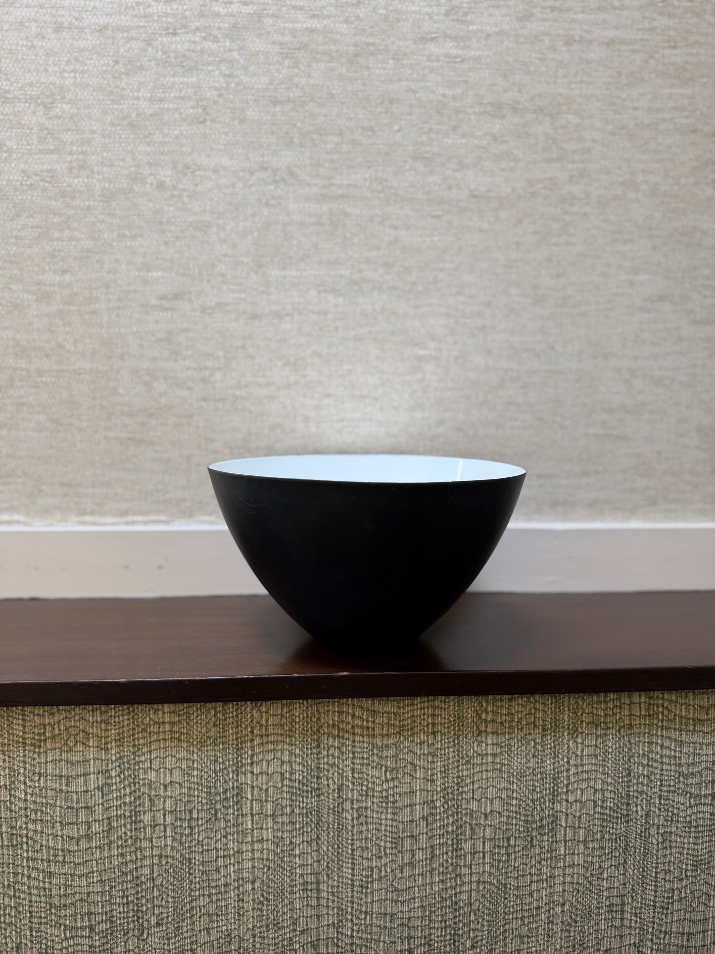 Black bowl on a wooden surface with a neutral background