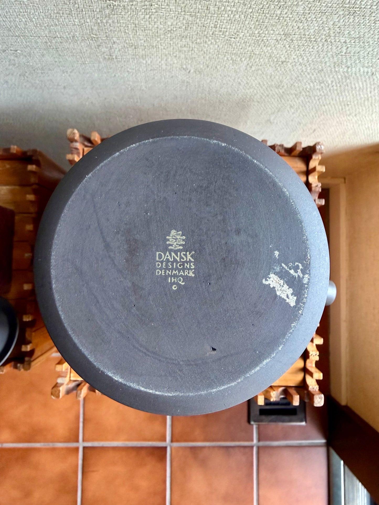 Black pot lid with 'Dansk Designs Denmark' branding on a textured surface.