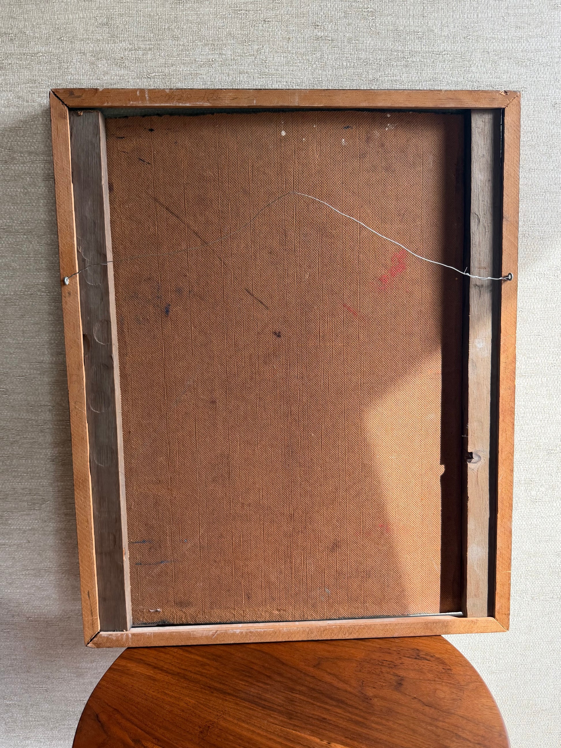 Back view of a wooden picture frame on a textured wall.