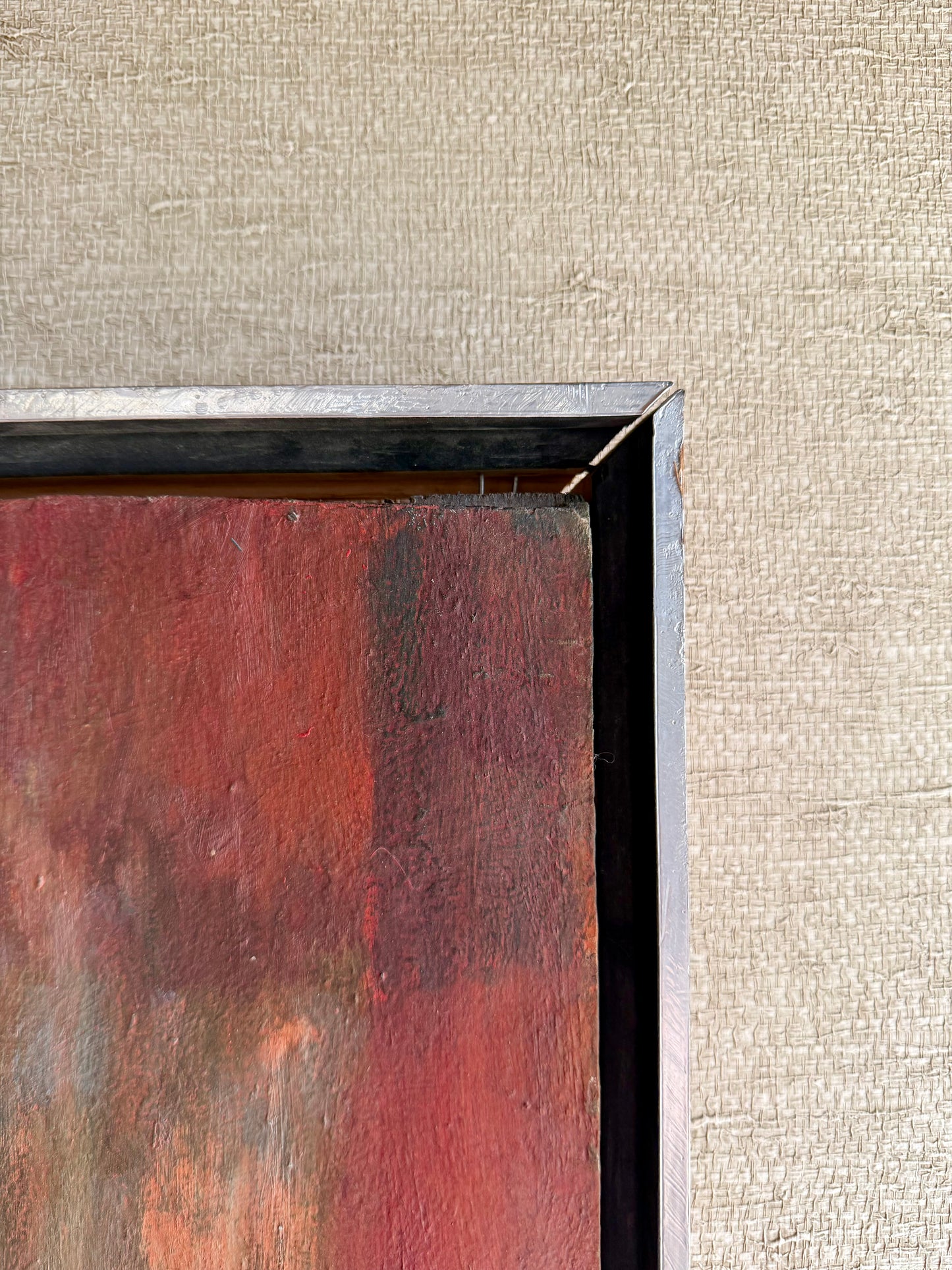 Abstract painting with a textured frame on a beige wall.