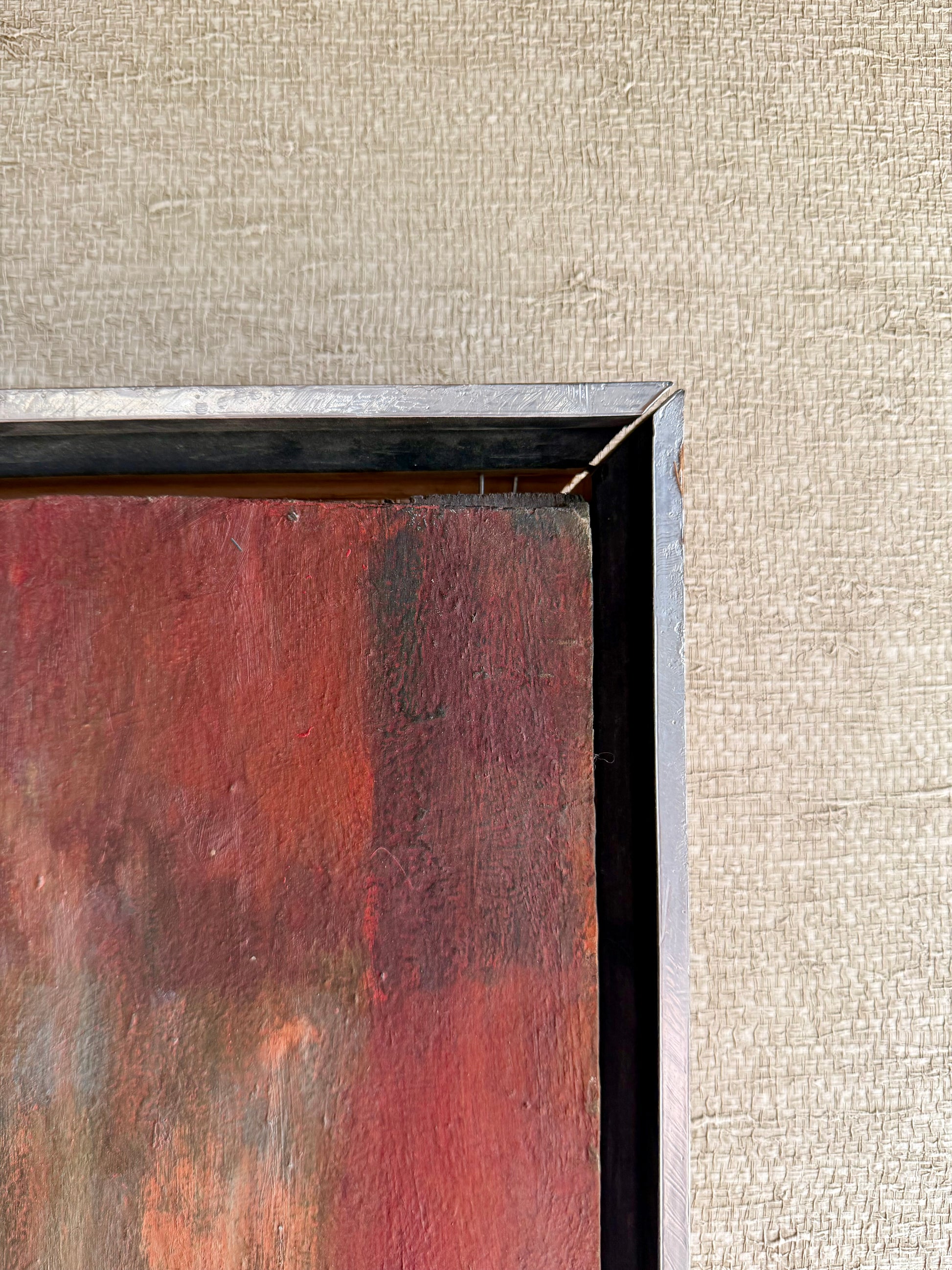 Abstract painting with a textured frame on a beige wall.