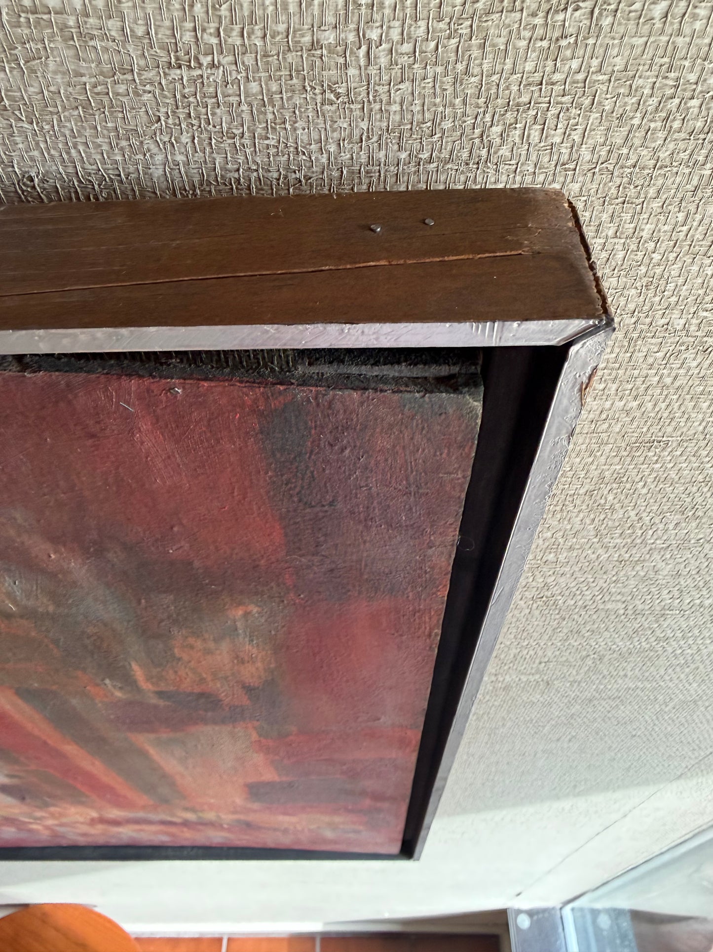 Close-up of a framed painting with a textured wall background