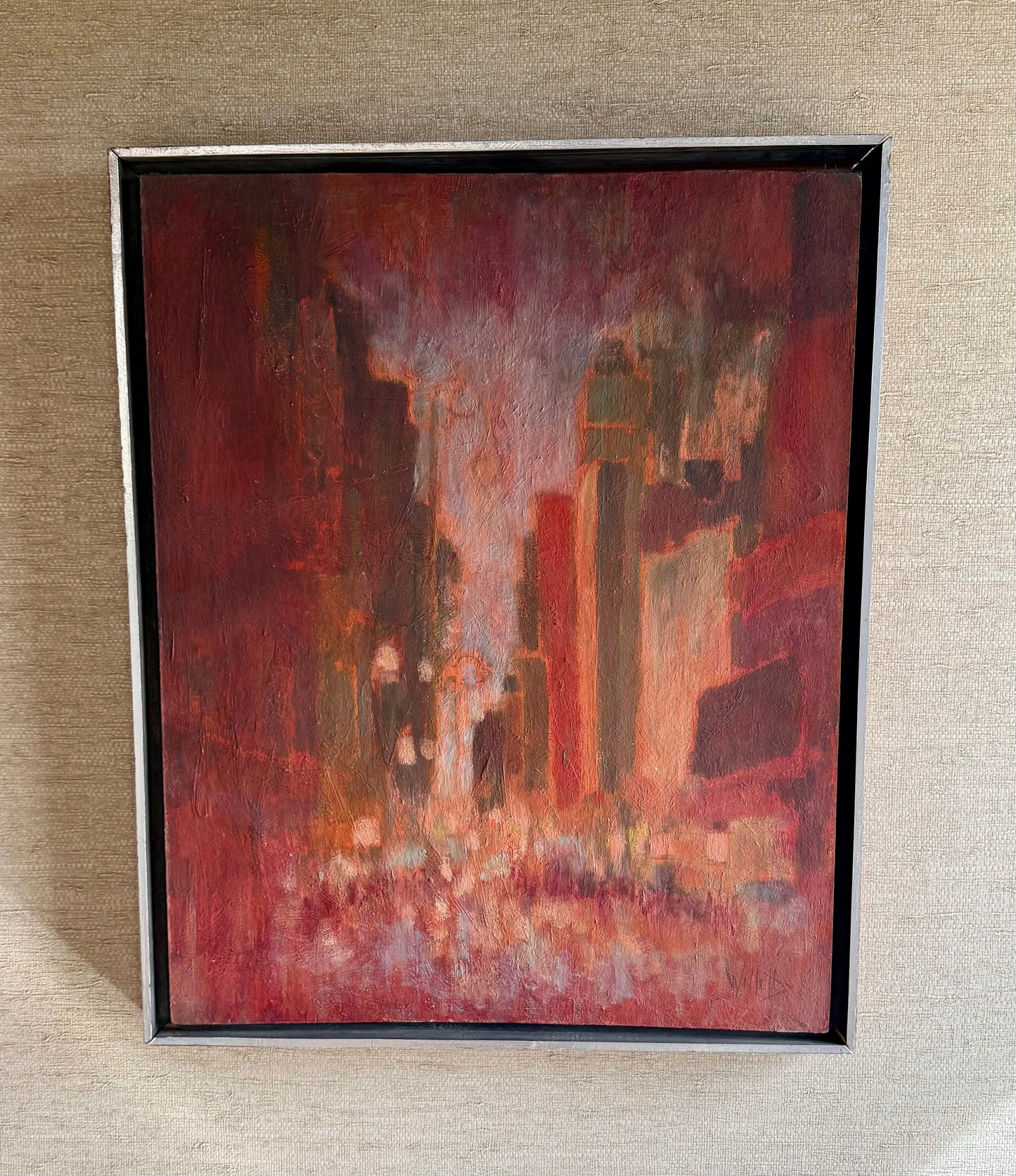 Framed abstract painting with warm tones on a textured wall.