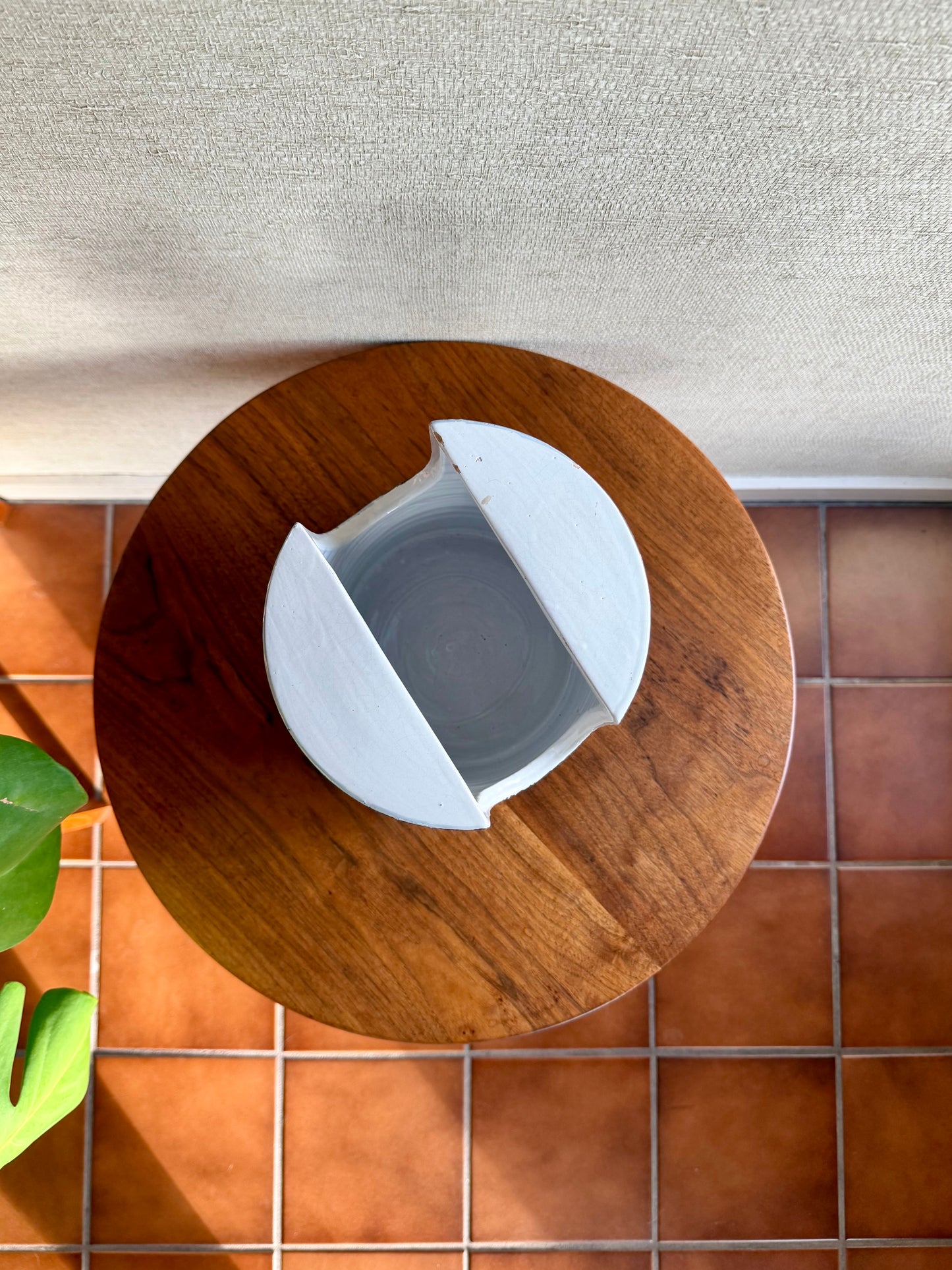 White ceramic bowl on a wooden stool with a tiled floor background