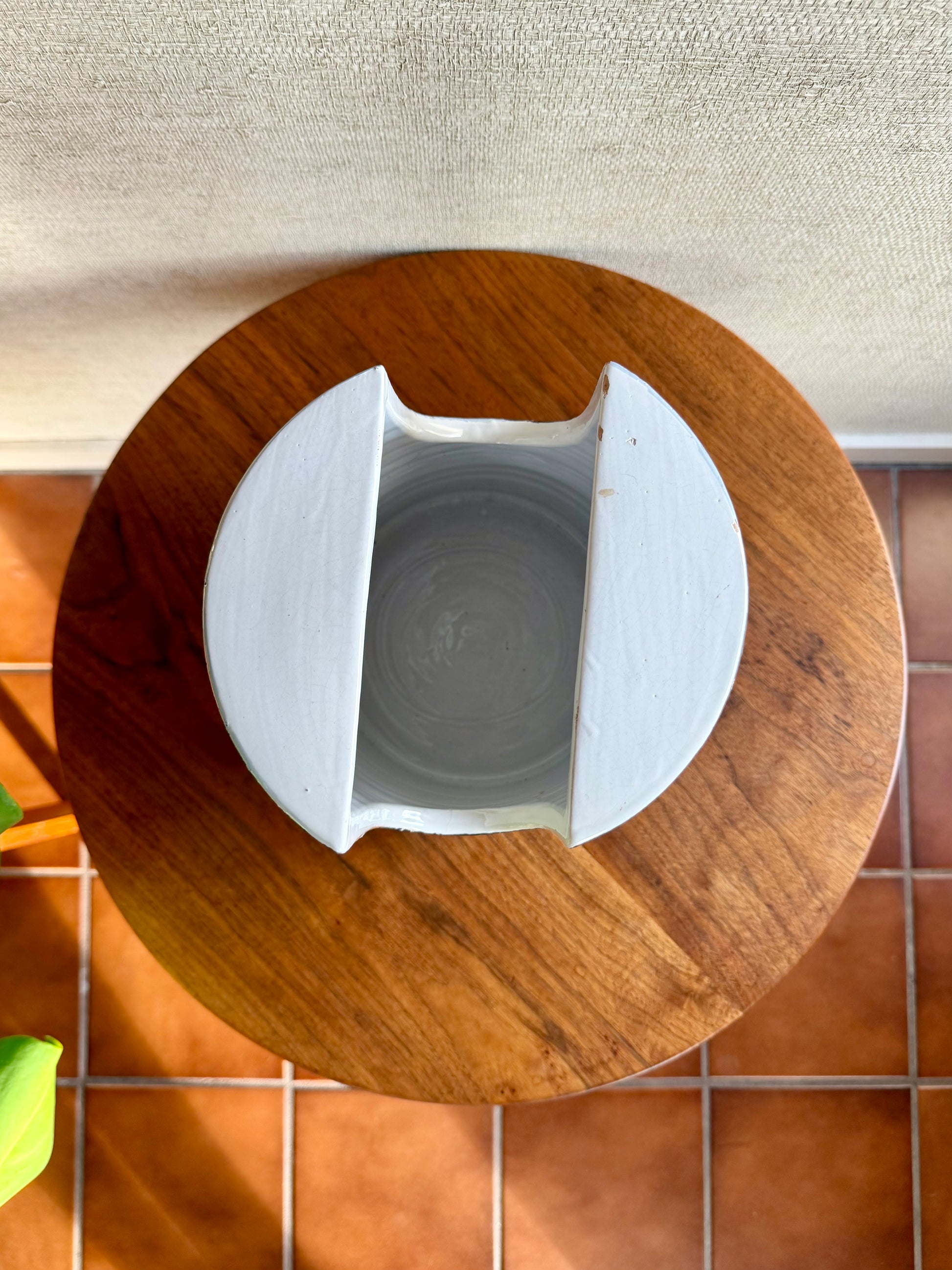 White ceramic container on a wooden lid with a tiled floor background