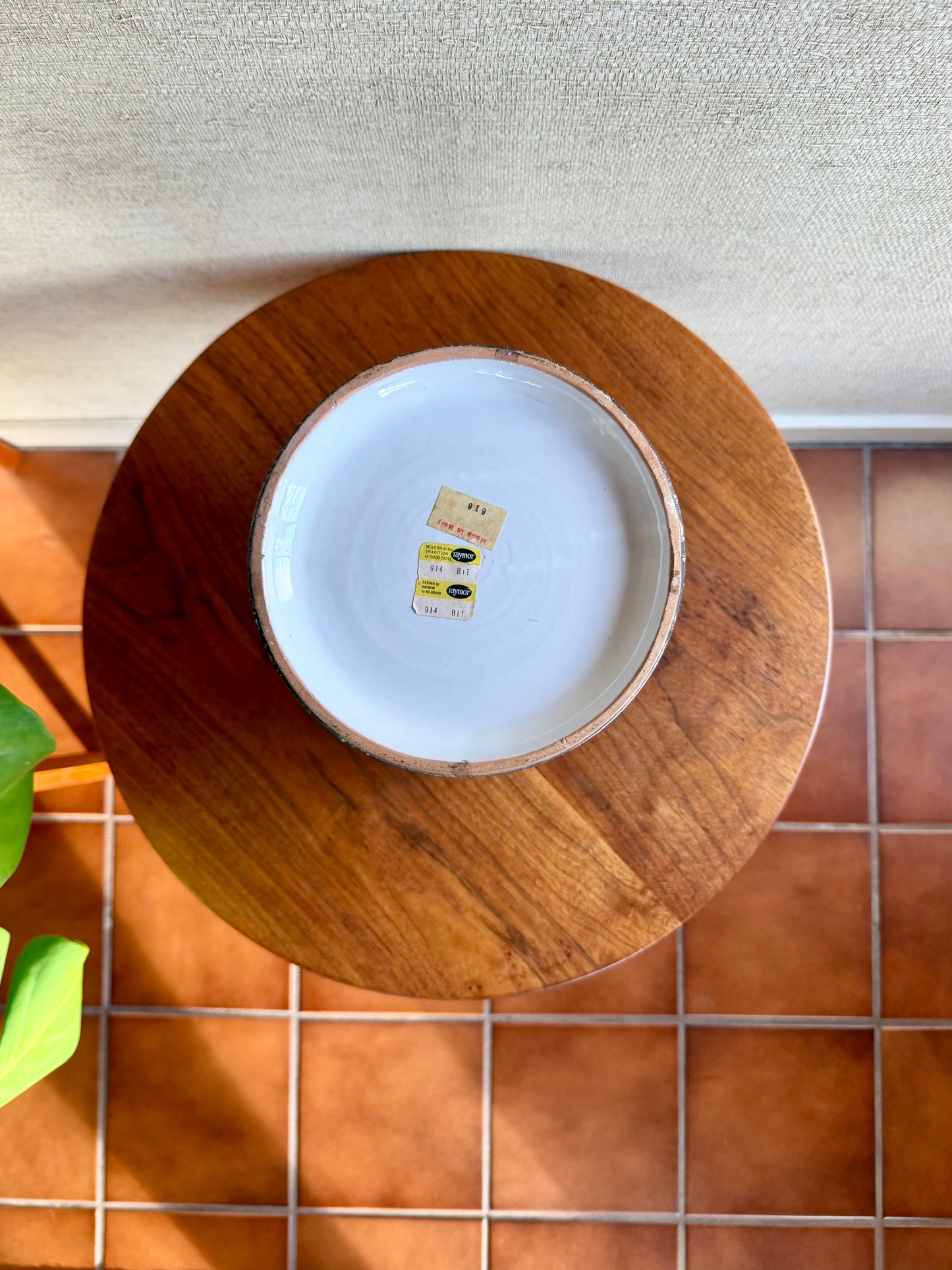 Wooden plate with a white ceramic plate inside on a tiled floor.