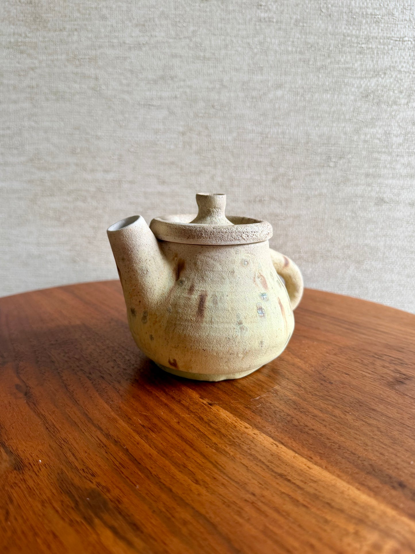 Ceramic teapot on a wooden surface with a neutral background