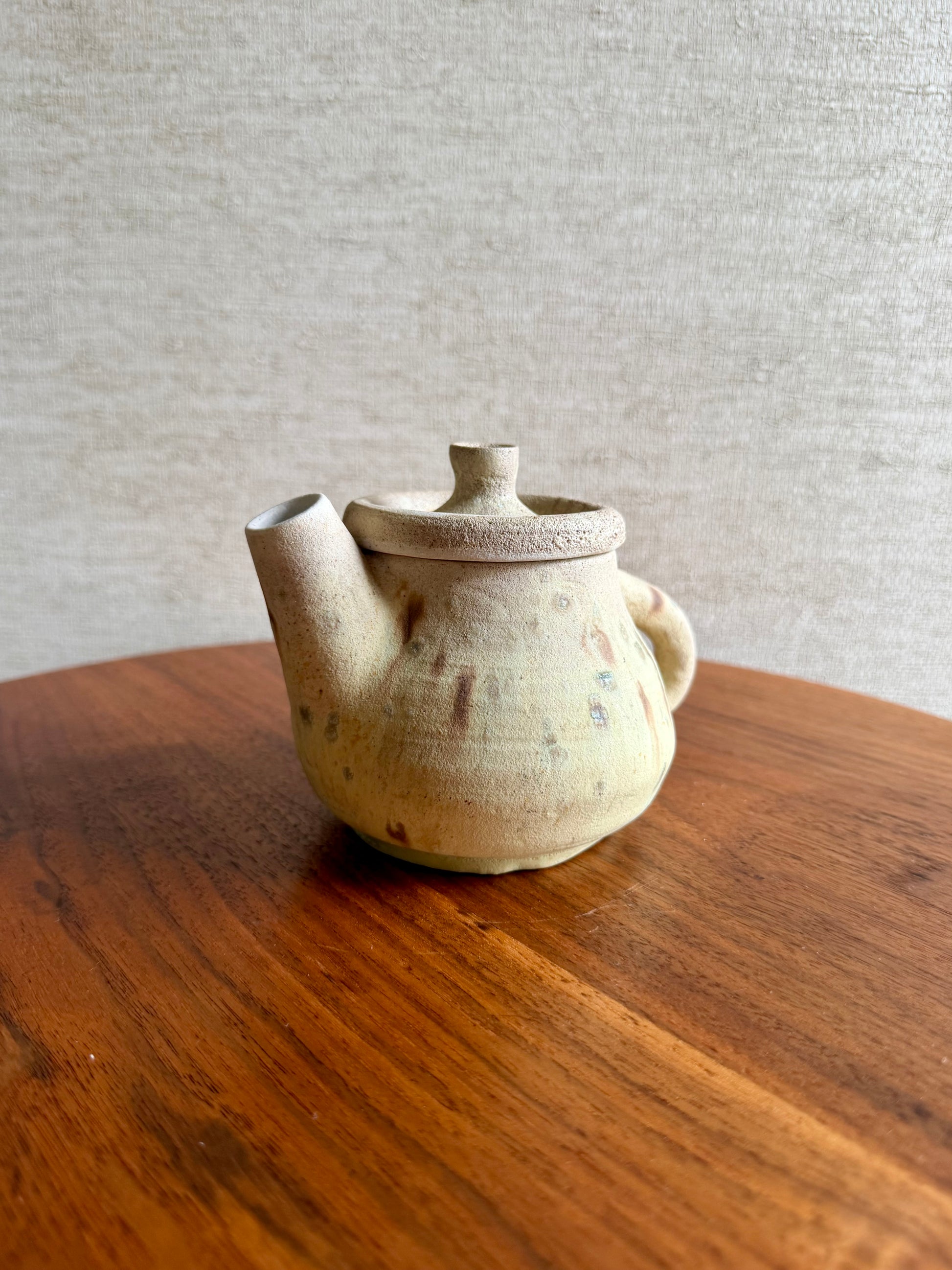 Ceramic teapot on a wooden surface with a neutral background