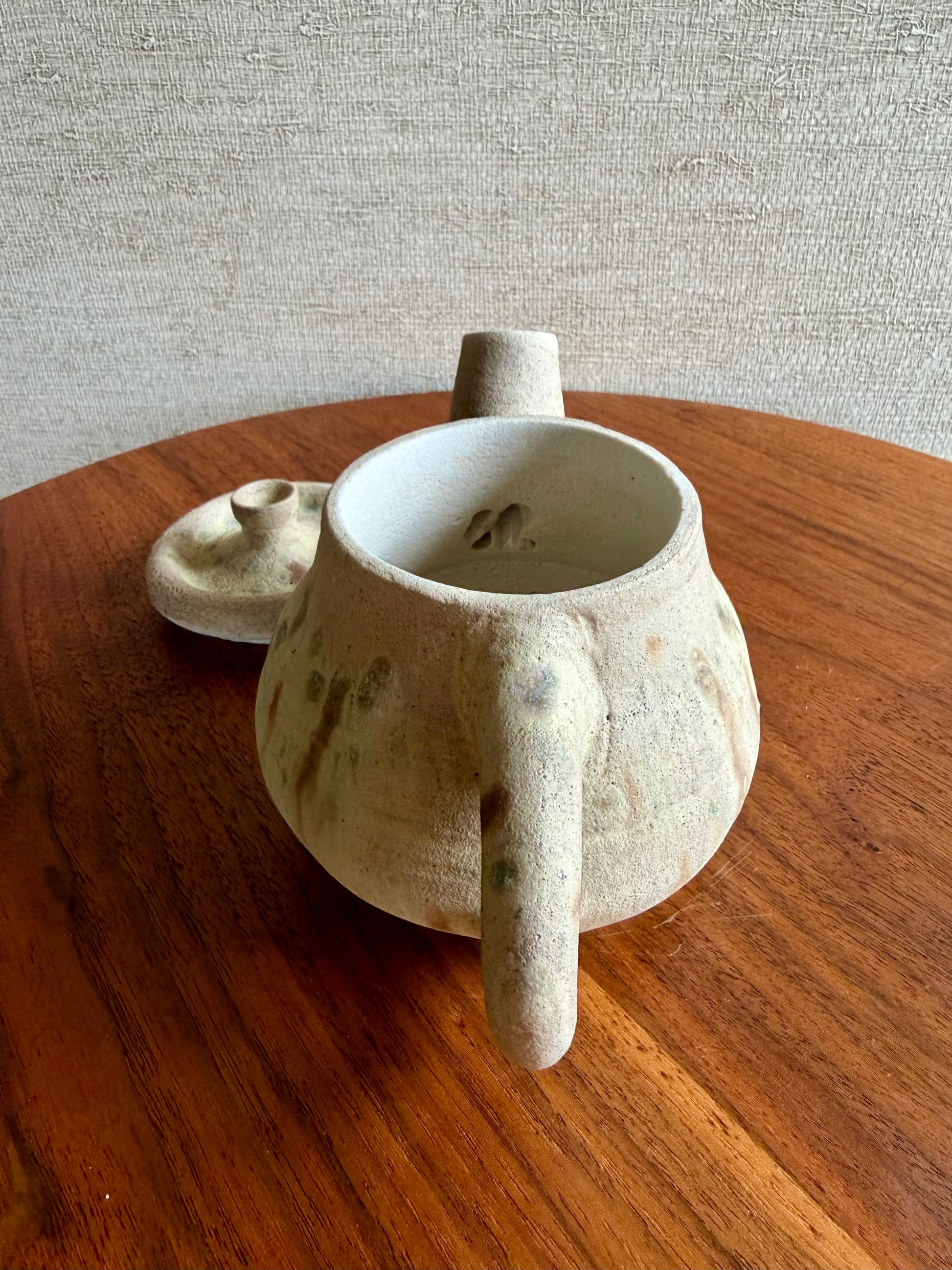 Ceramic teapot with a small spout on a wooden surface