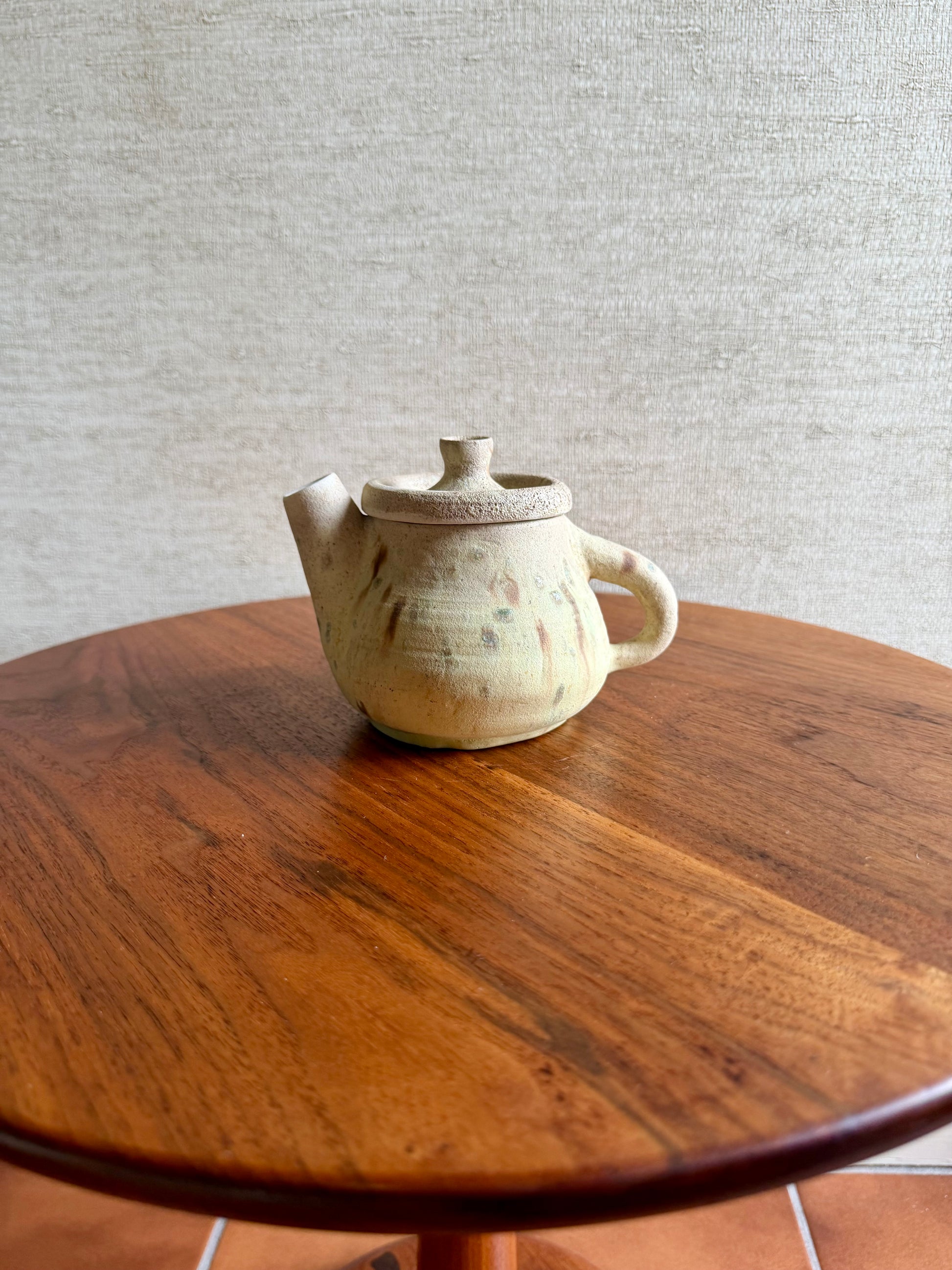 Ceramic teapot on a wooden table with a gray textured wall background
