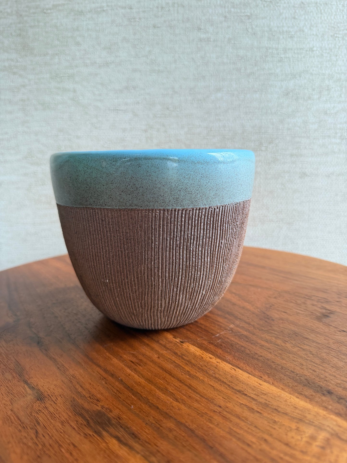 Close-up of a textured brown object on a wooden surface with a light gray background