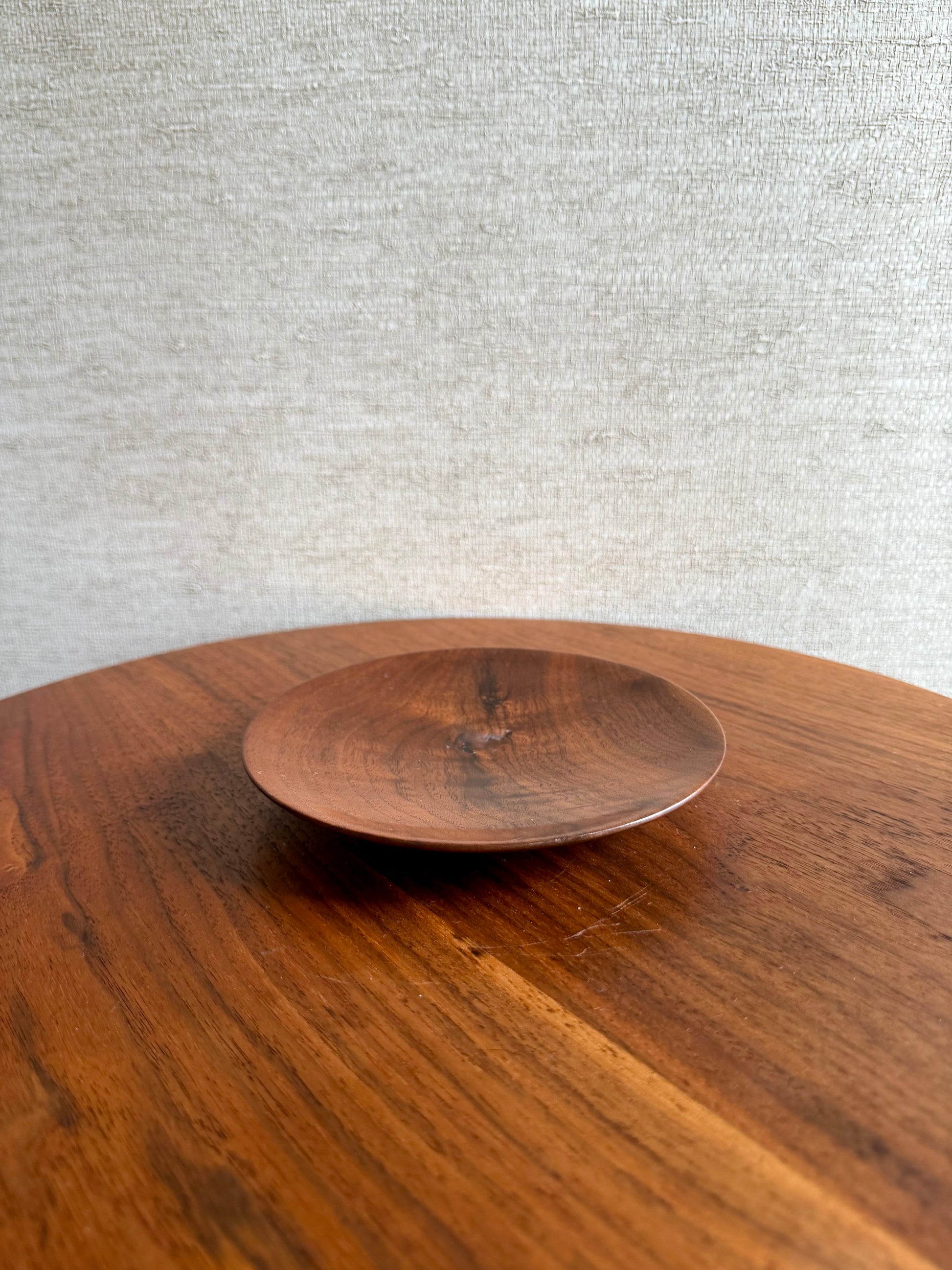 Wooden table with a smaller wooden plate on top against a textured gray wall.