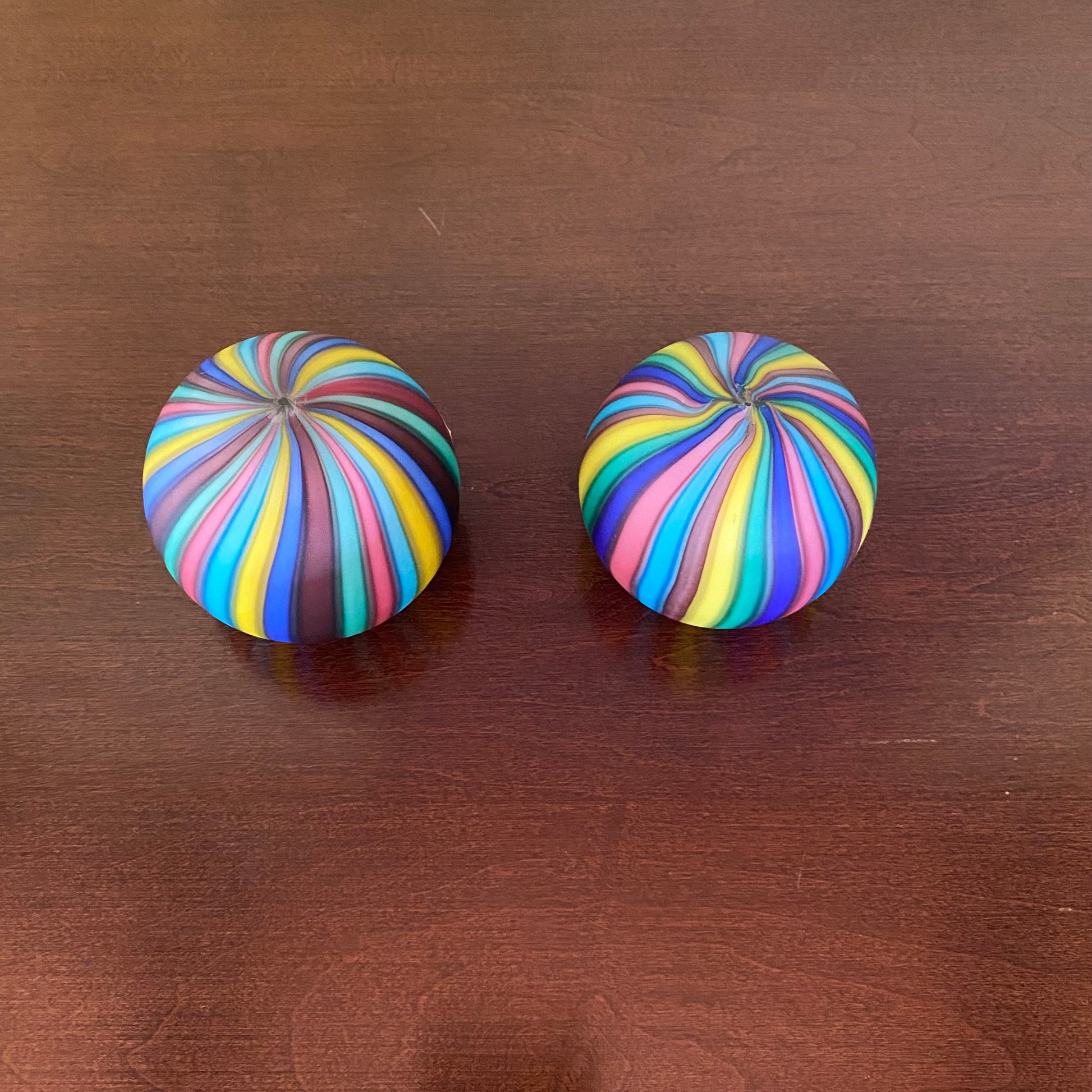 Two colorful striped knobs on a wooden surface