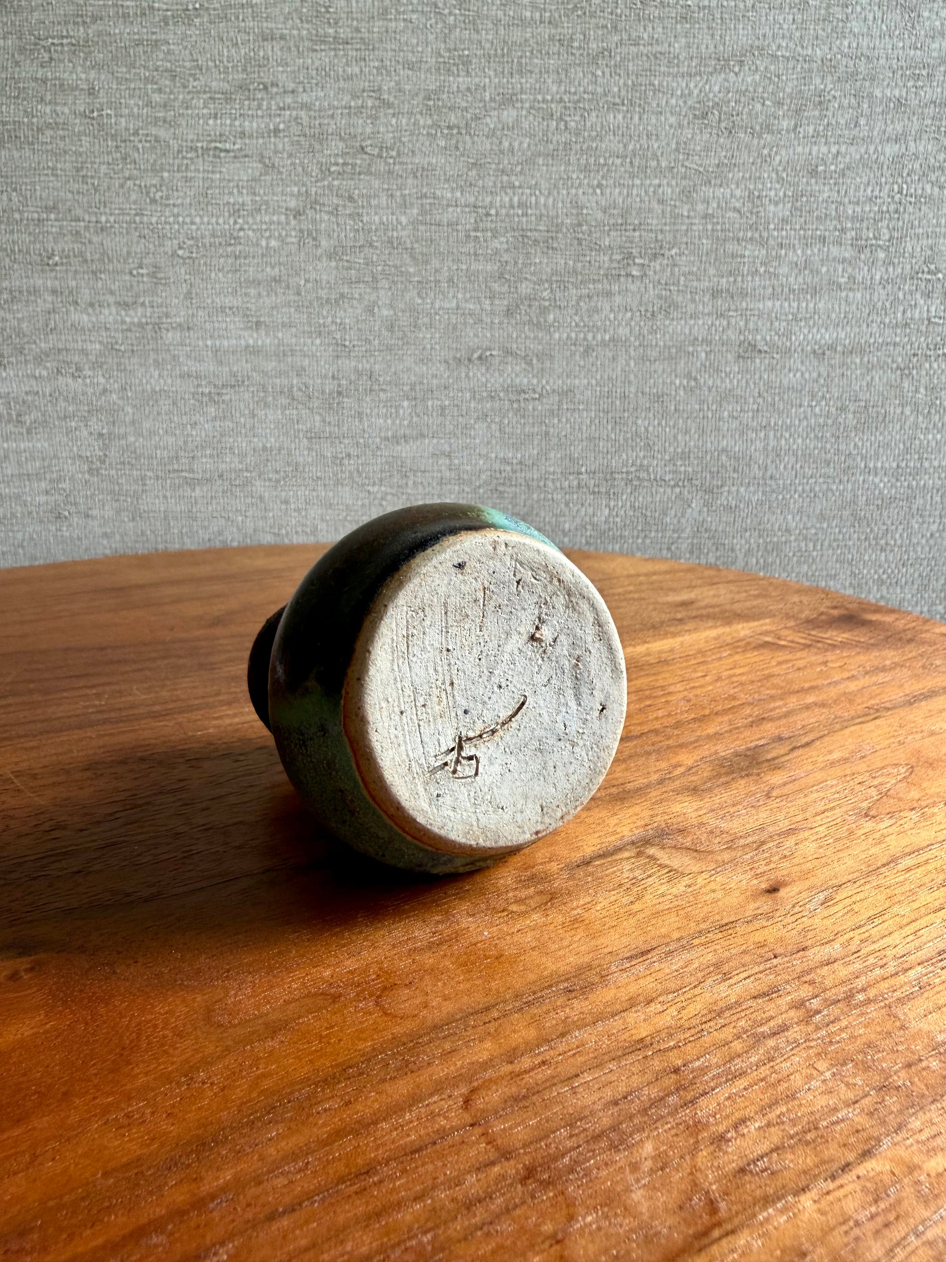 Round ceramic object with a textured surface on a wooden surface against a gray background