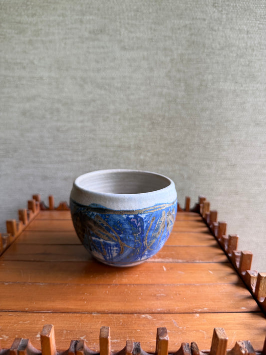 Ceramic bowl with blue and gold design on a wooden surface