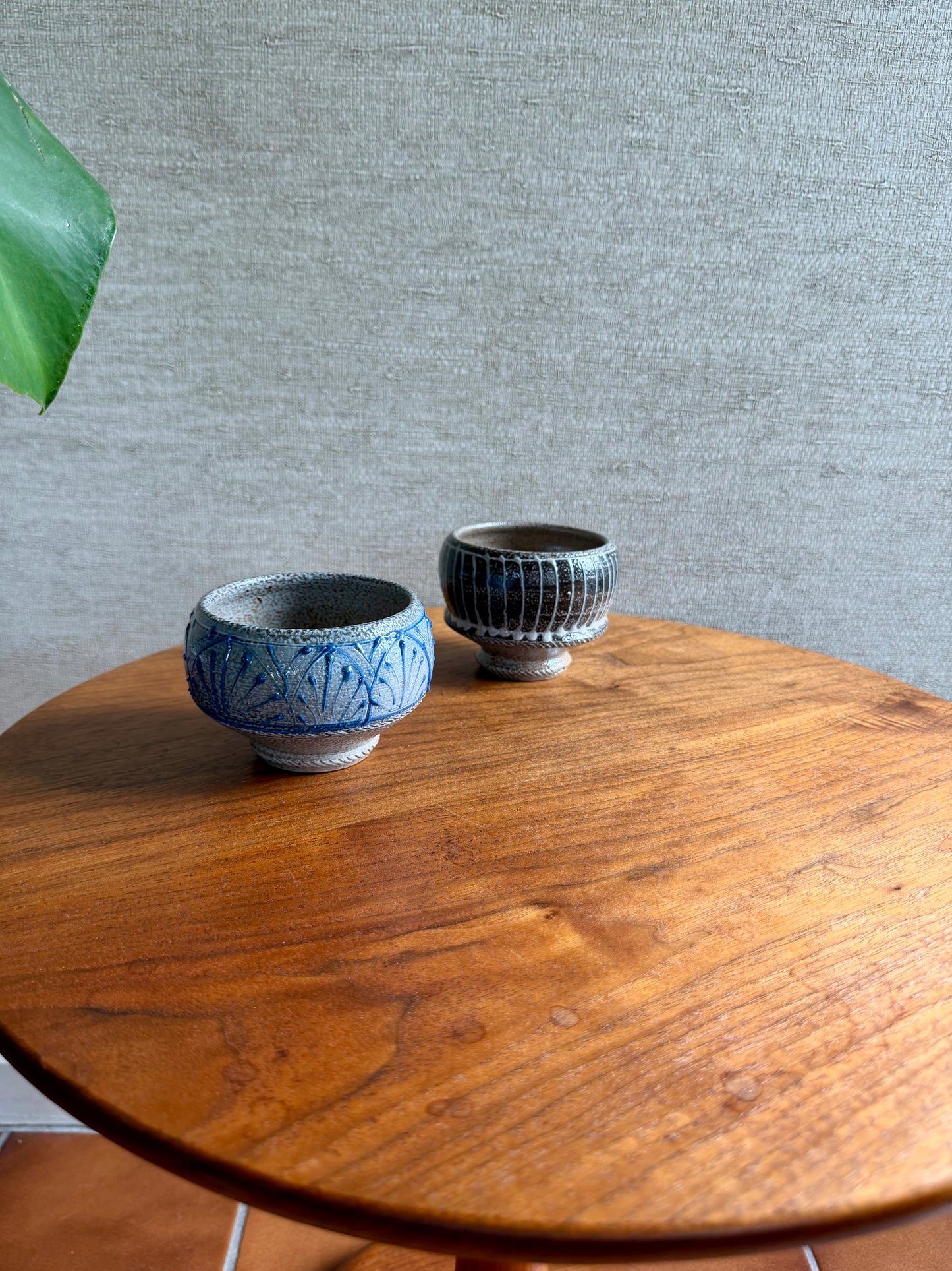 Two ceramic bowls on a wooden table with a gray textured wall in the background.