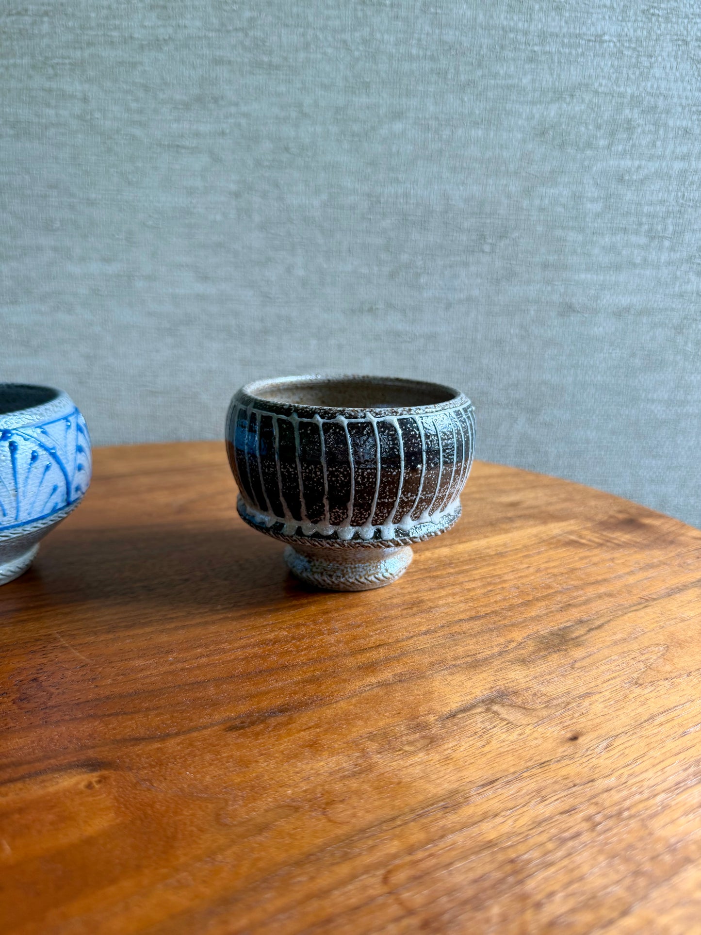 Two ceramic cups on a wooden surface with a gray textured background
