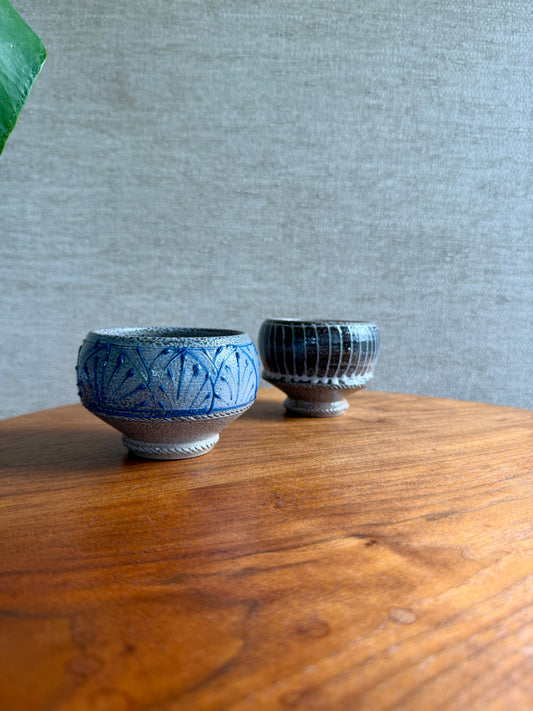 Two blue ceramic bowls on a wooden surface with a gray textured wall in the background.