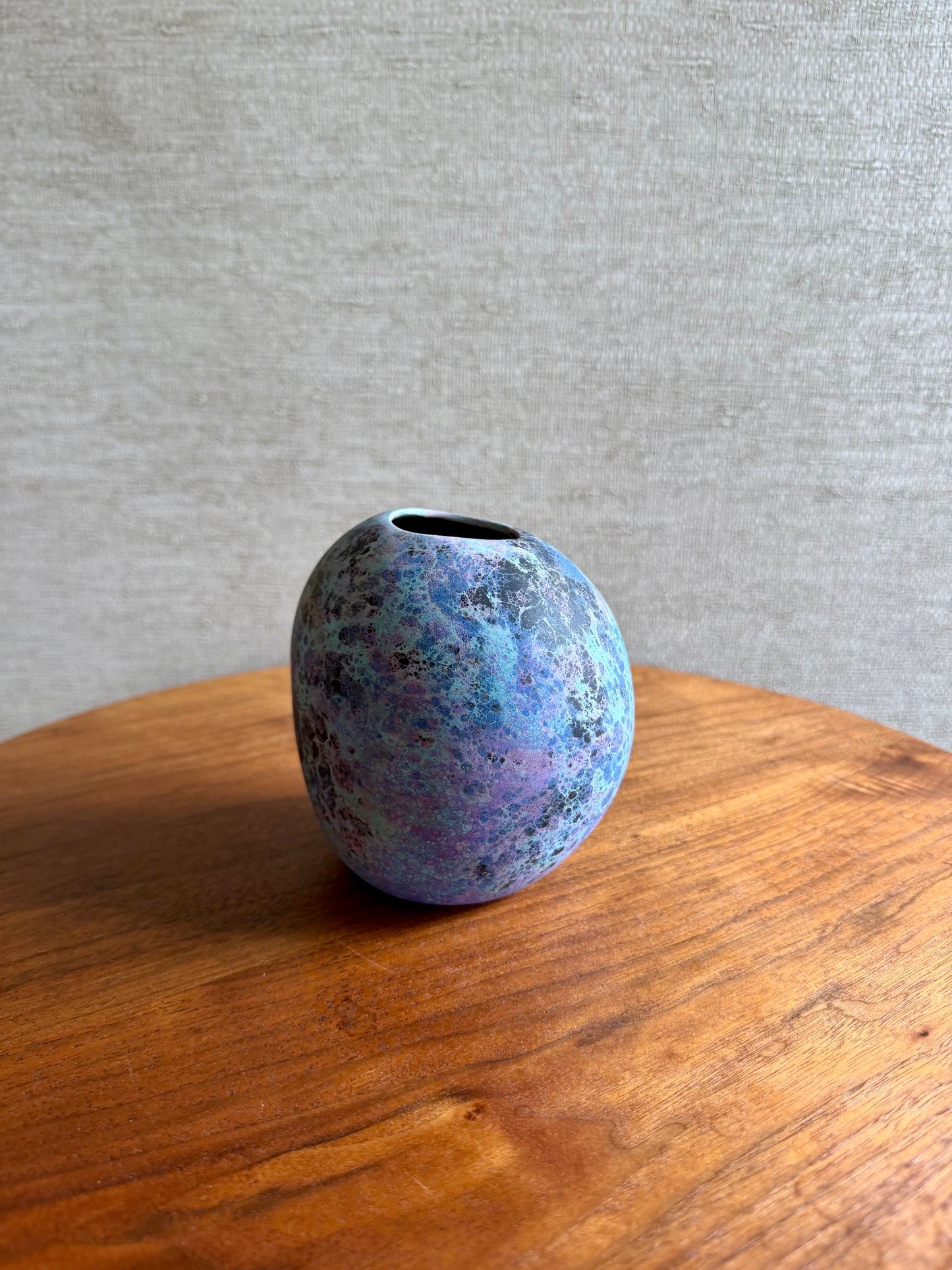 Blue ceramic vase on a wooden surface with a gray textured background