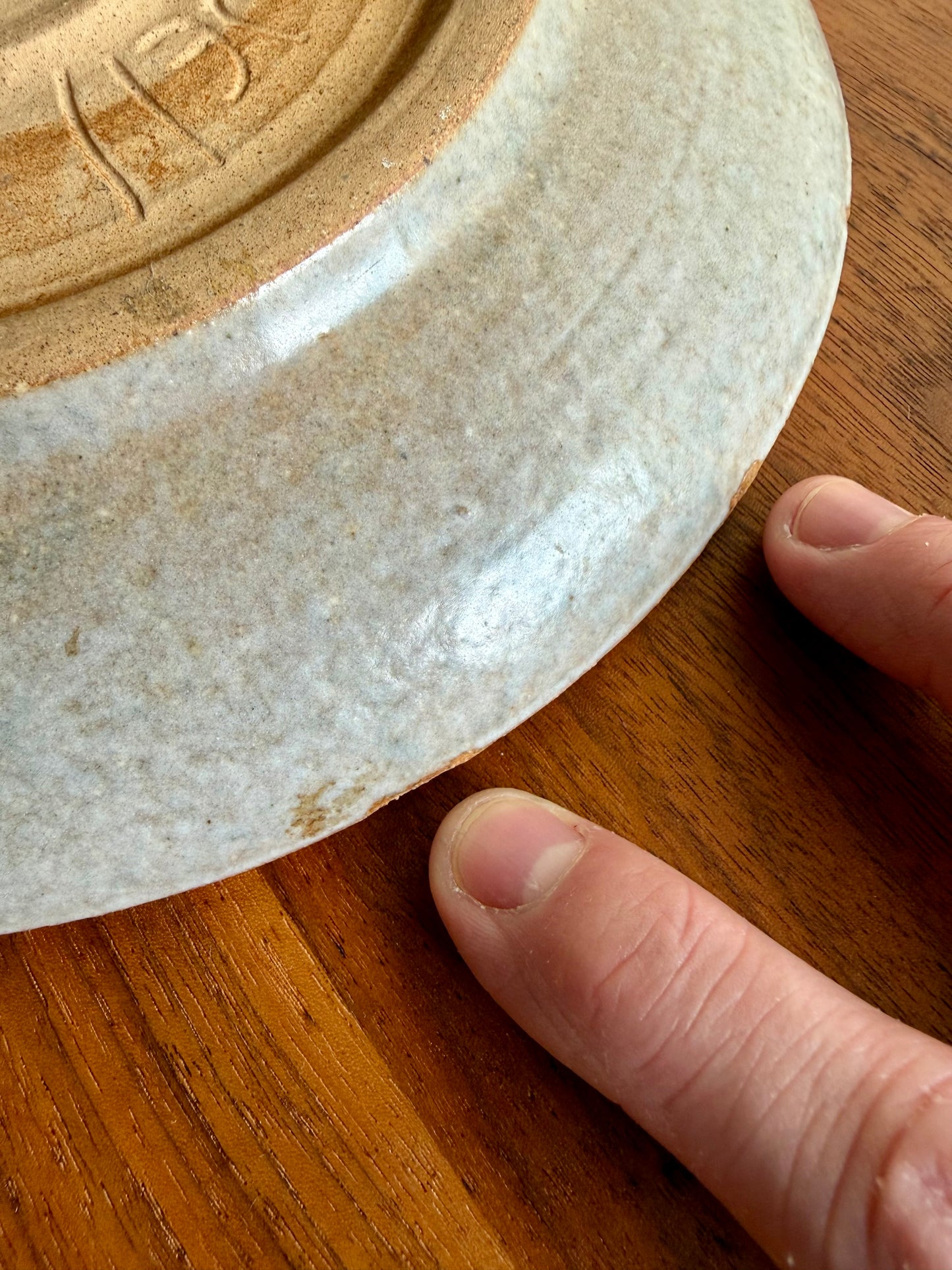 Close-up of a ceramic plate with an embossed design on a wooden surface.