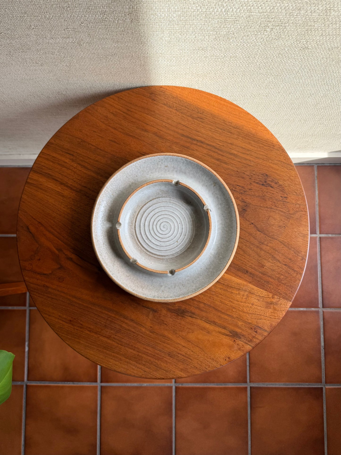 Round wooden table with a ceramic plate on a tiled floor