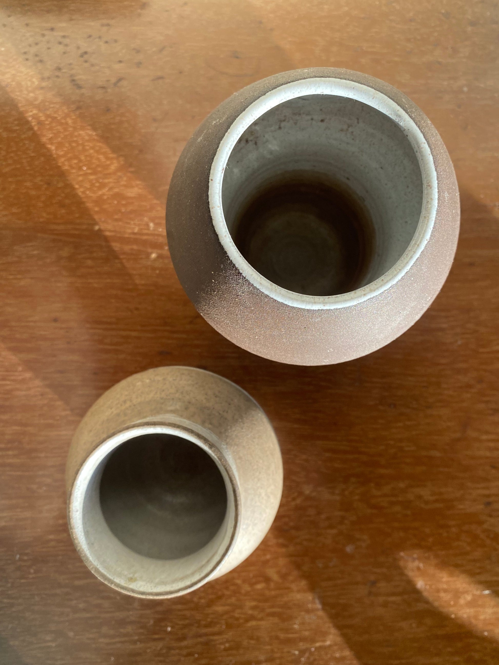 Two small ceramic pots on a wooden surface