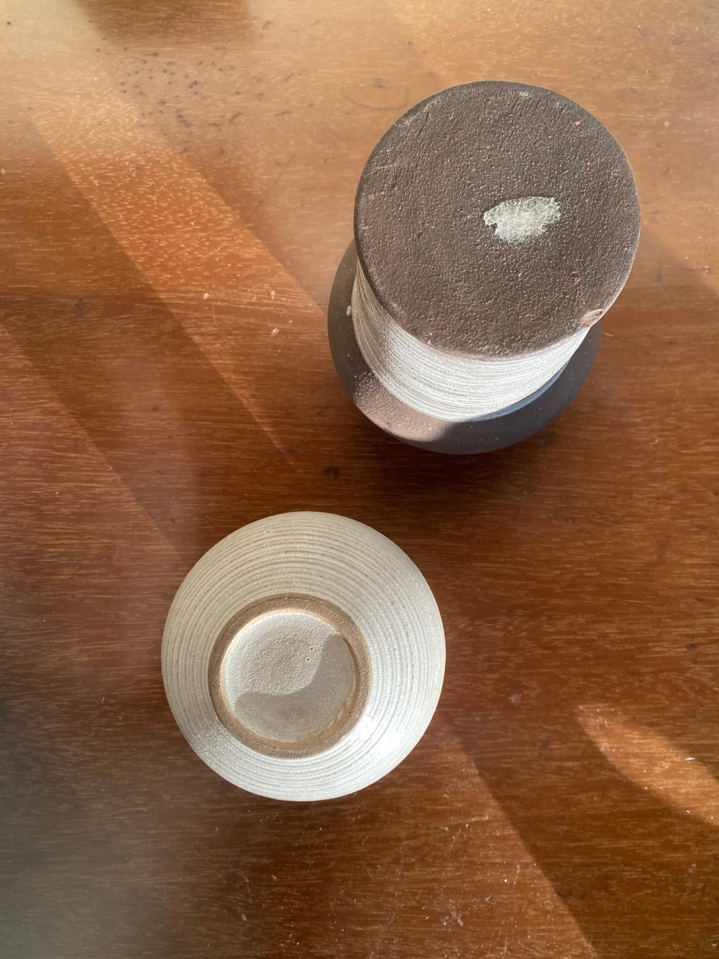 Two cylindrical objects on a wooden surface with visible wear.