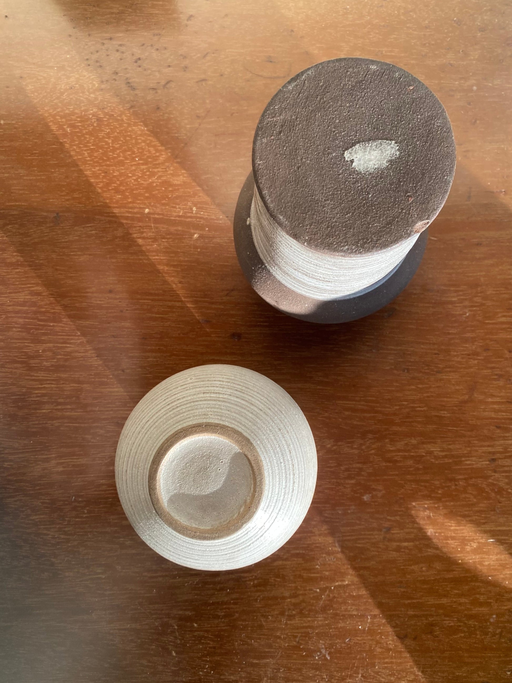 Two cylindrical objects on a wooden surface with visible wear.