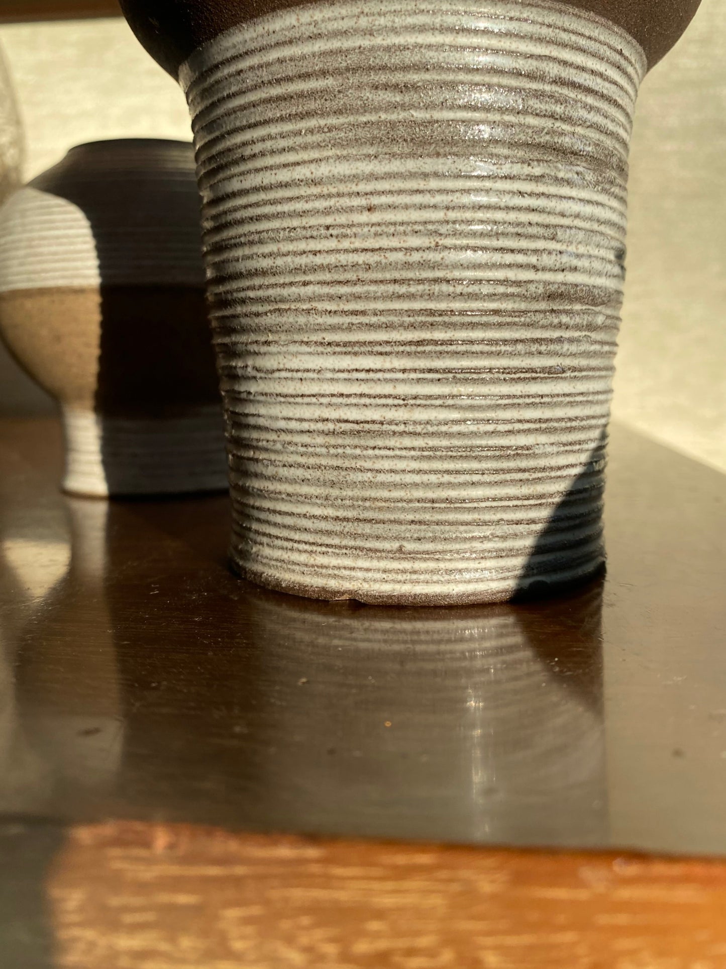Textured vase on a reflective surface with a blurred background