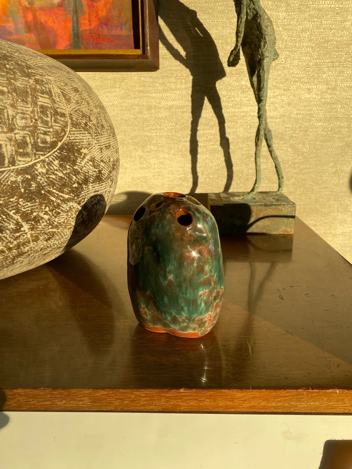 Decorative objects including a textured sphere and a green ceramic item against a textured wall.