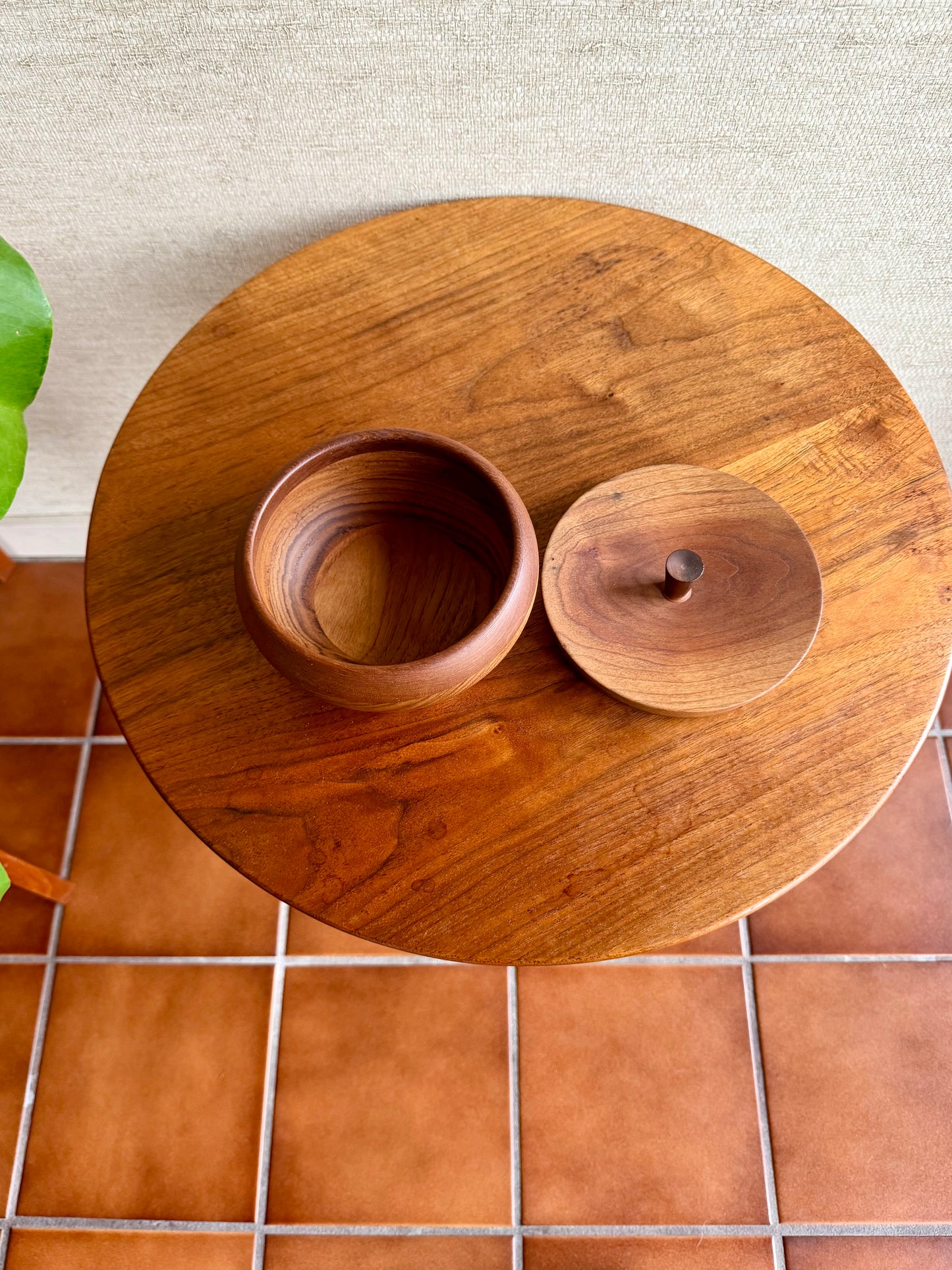 Wooden bowl and lid on a wooden surface with a tiled floor background