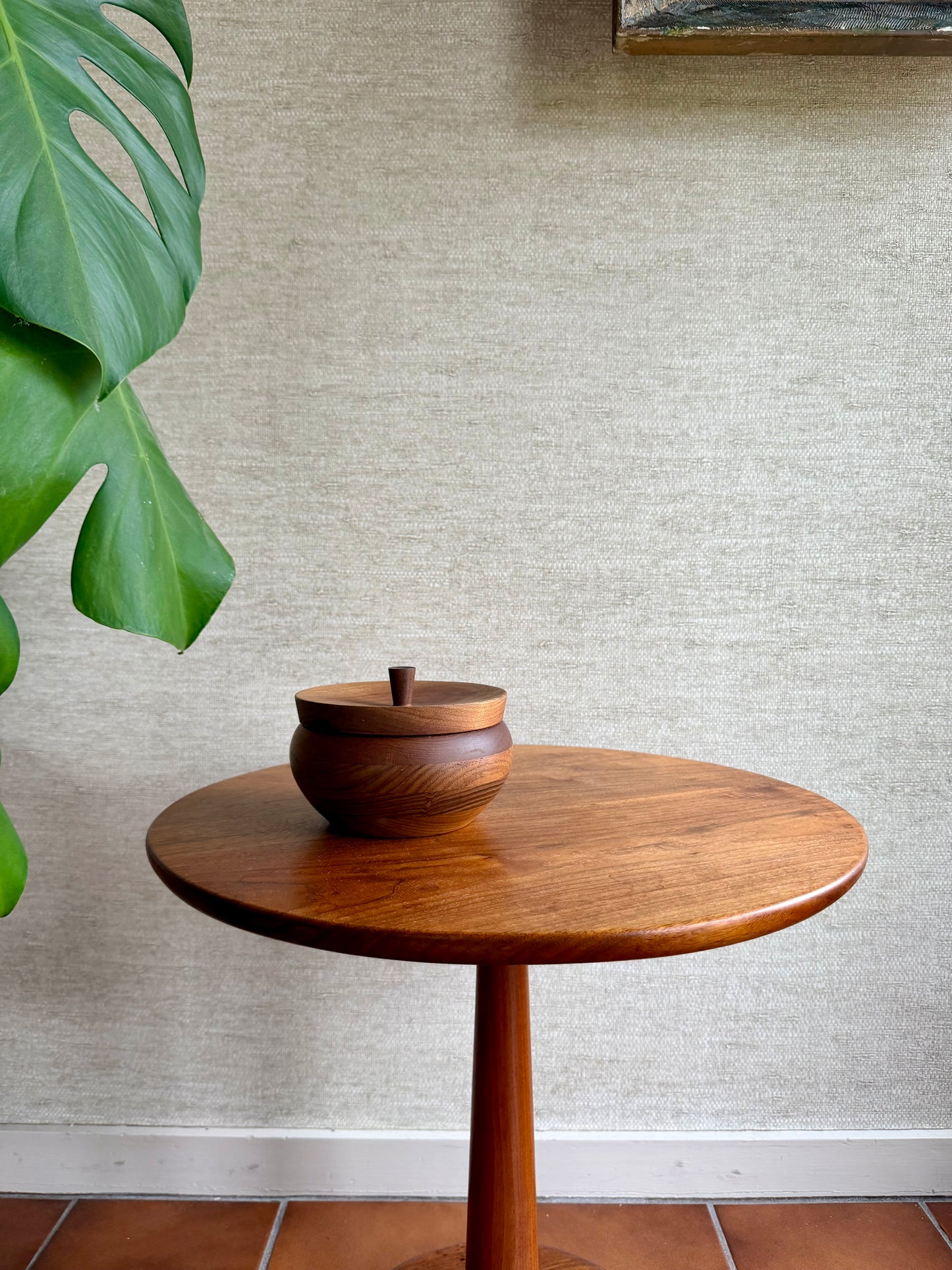 Wooden side table with a decorative bowl against a textured wall.
